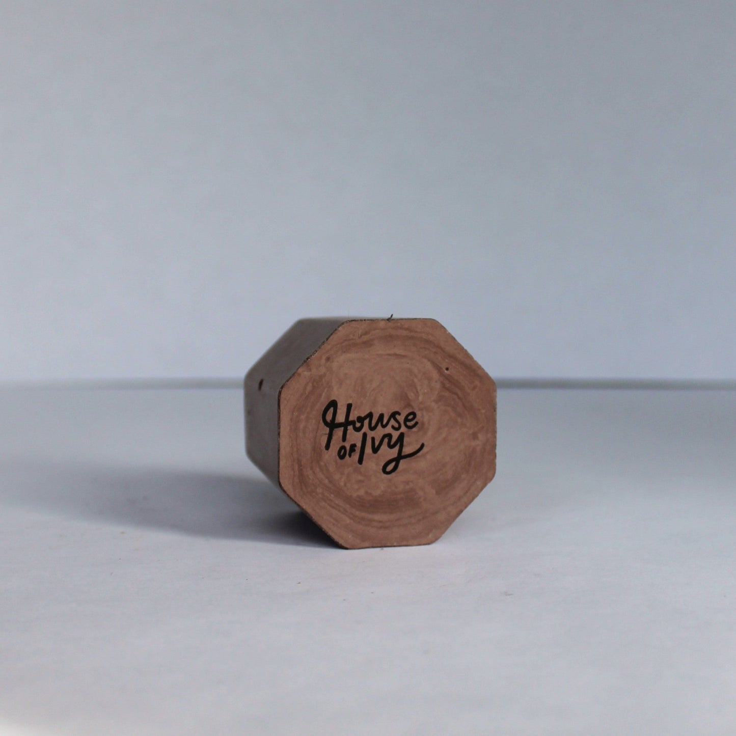 Bottom of a brown hexagonal small concrete dish with 'House of Ivy' branding on a white background