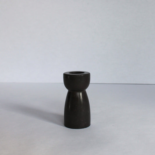 Black concrete candle stick holder on a white surface with a white background