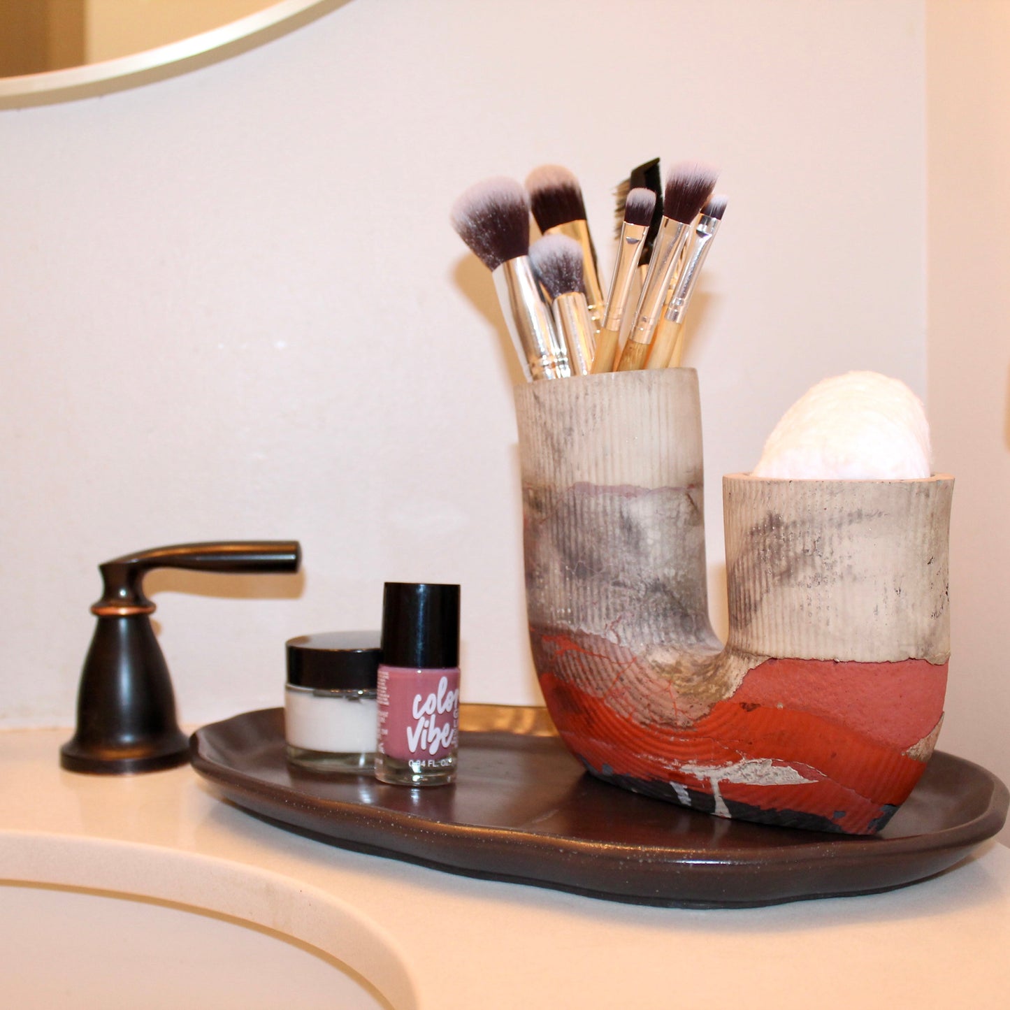 Bathroom counter with makeup brushes in a holder cotton makeup remover pads.