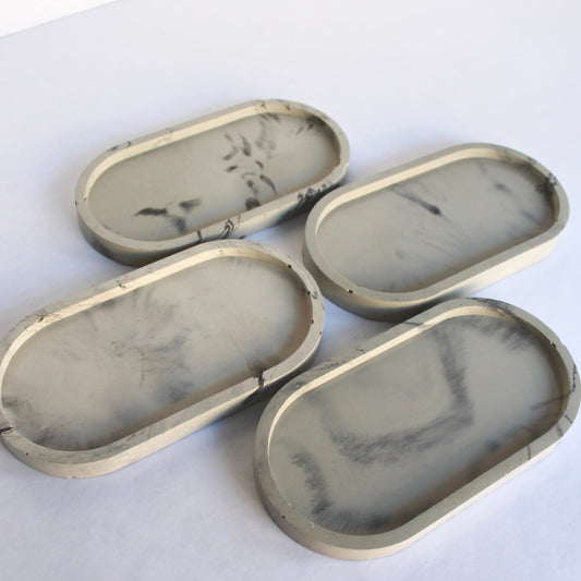 Four marbled concrete oval trays on a white background