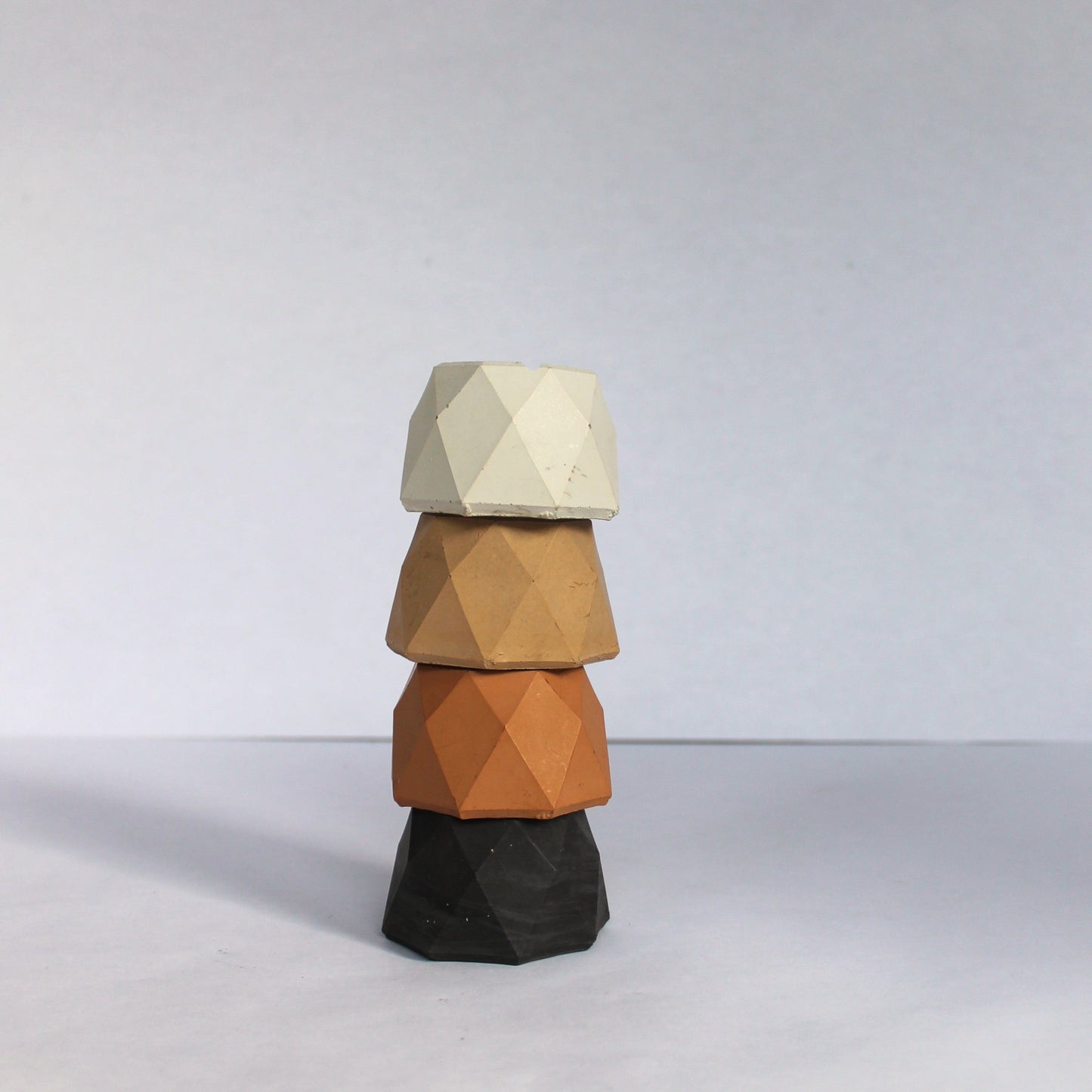 Stack of geometrically shaped small concrete jewelry dishes on a white background