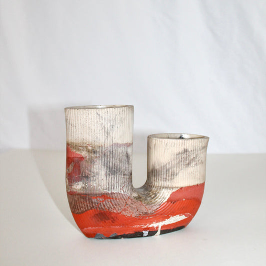 Concrete vase with orange and white abstract design on a white background