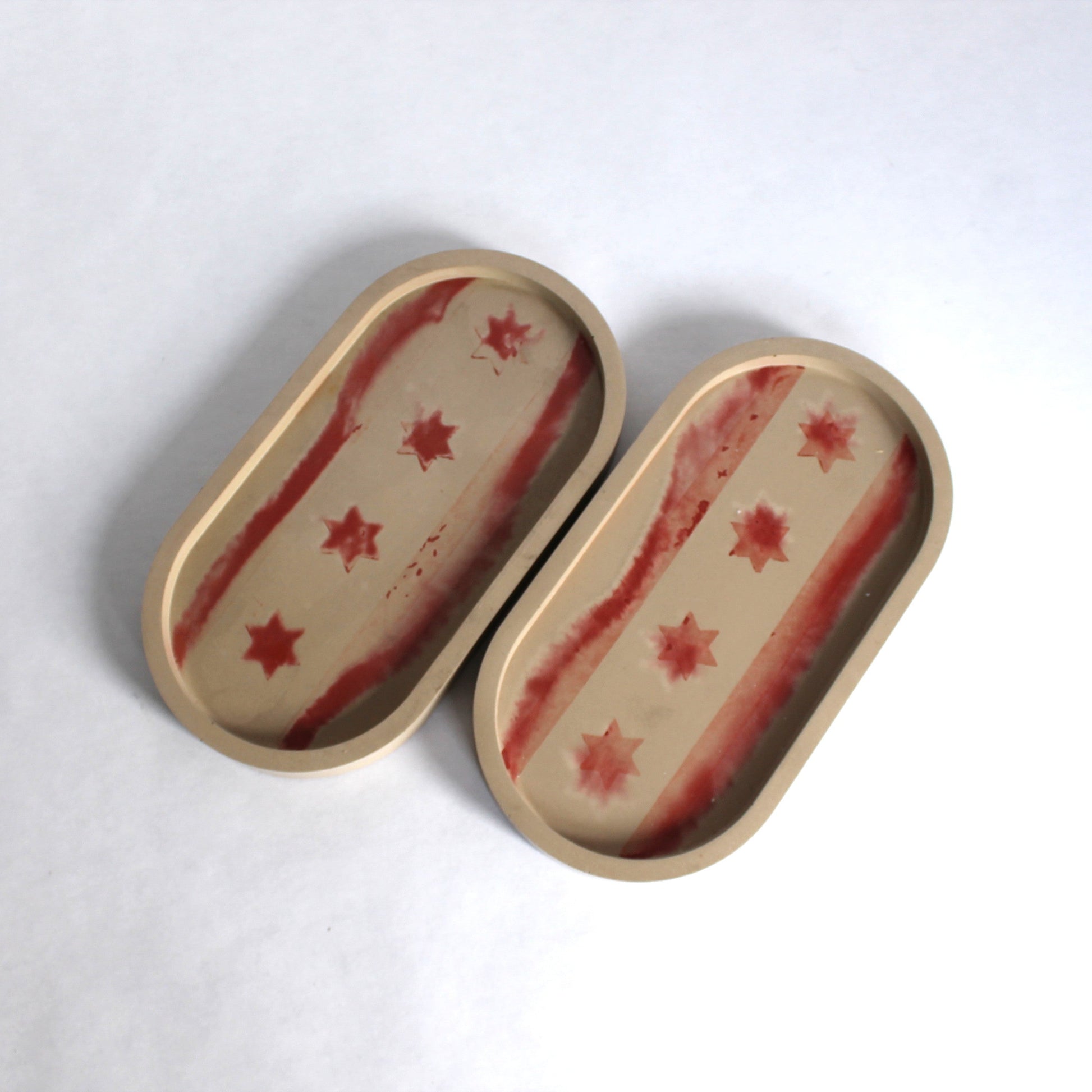 Two oval trays with abstract Chicago flag pattern on a white background
