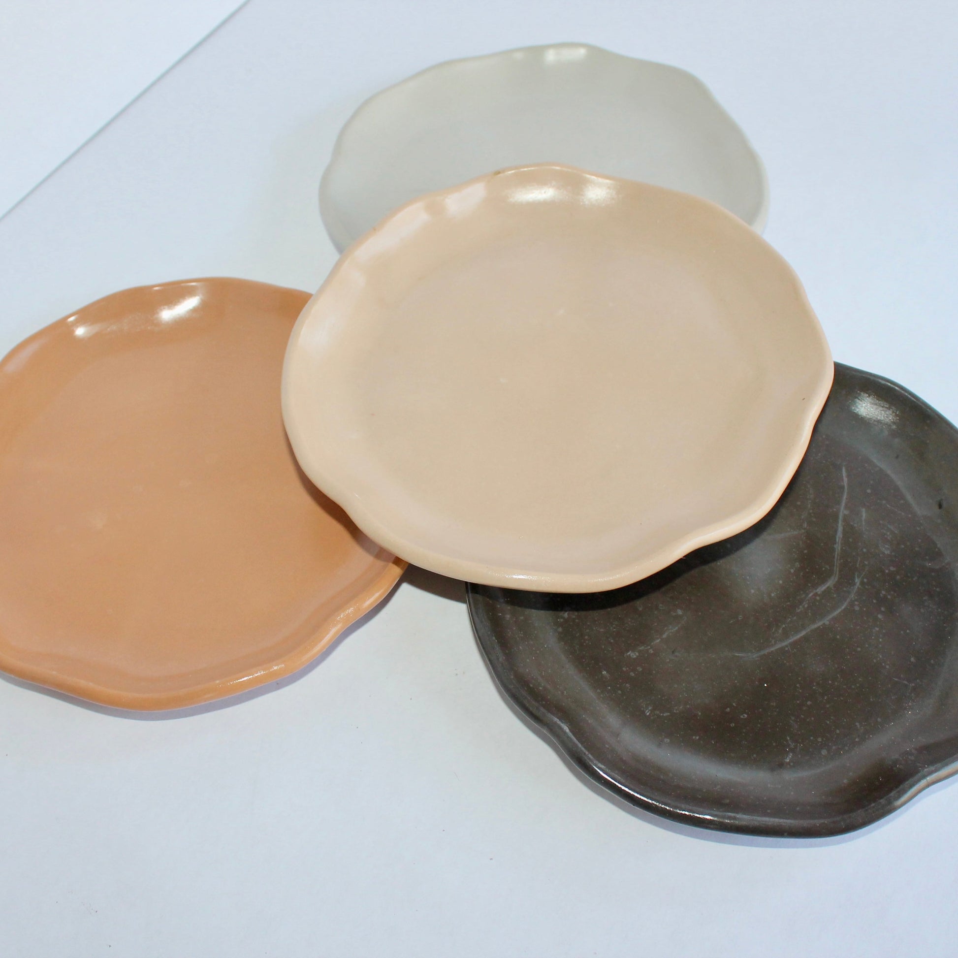 Four concrete round plates in different colors on a white surface