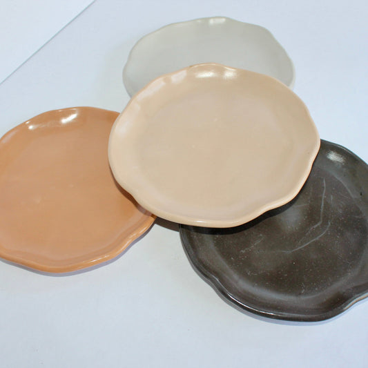 Four concrete round plates in different colors on a white surface