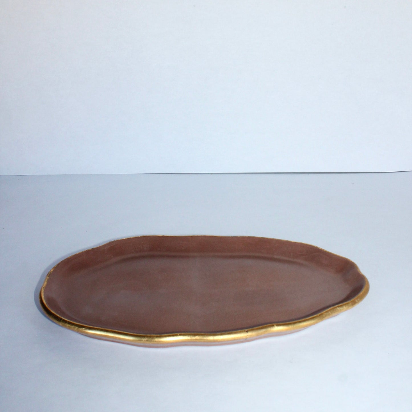 Mocha brown concrete tray with gold rim on a white background