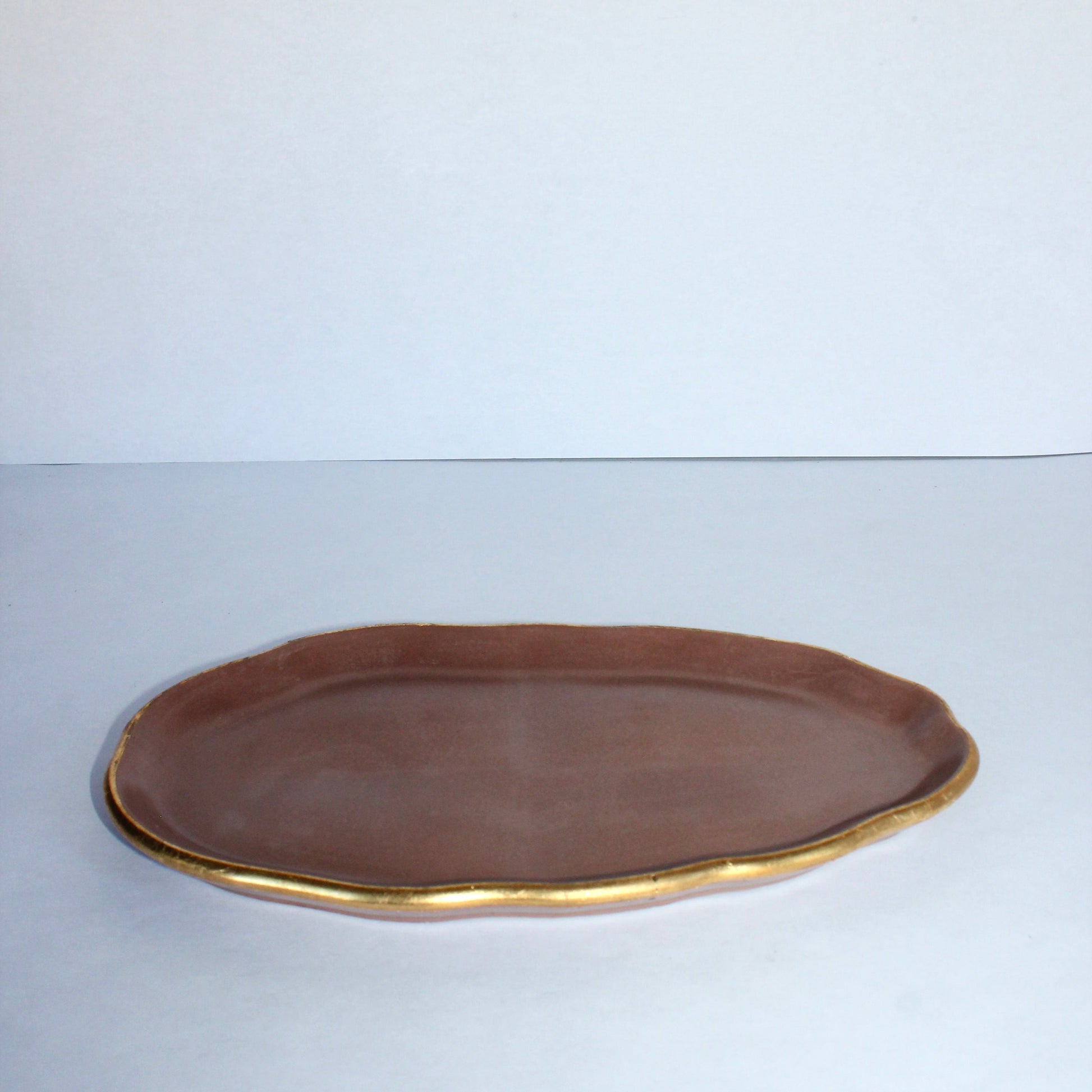 Mocha brown concrete tray with gold rim on a white background