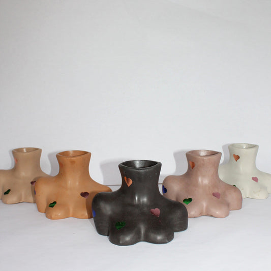 Set of five concrete female body shaped vases in various colors on a white surface