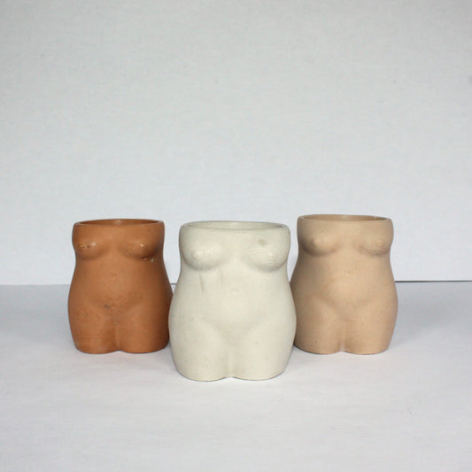 Three abstract torso-shaped vases in different neutral colors on a white background