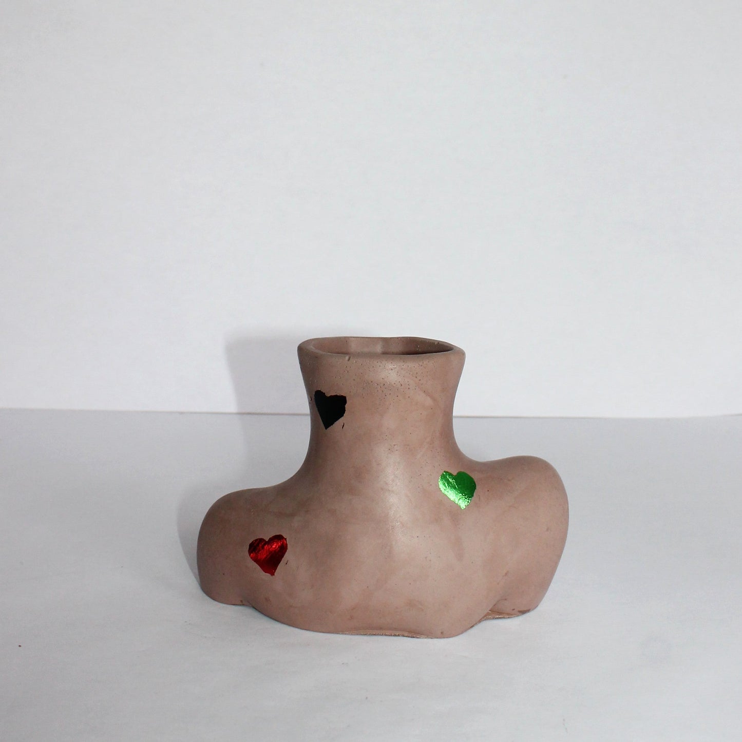 Concrete vase with colorful heart shapes on a white background