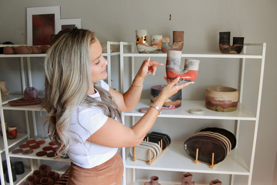 concrete artist holding and pointing to a concrete vase to emphasize colors and details