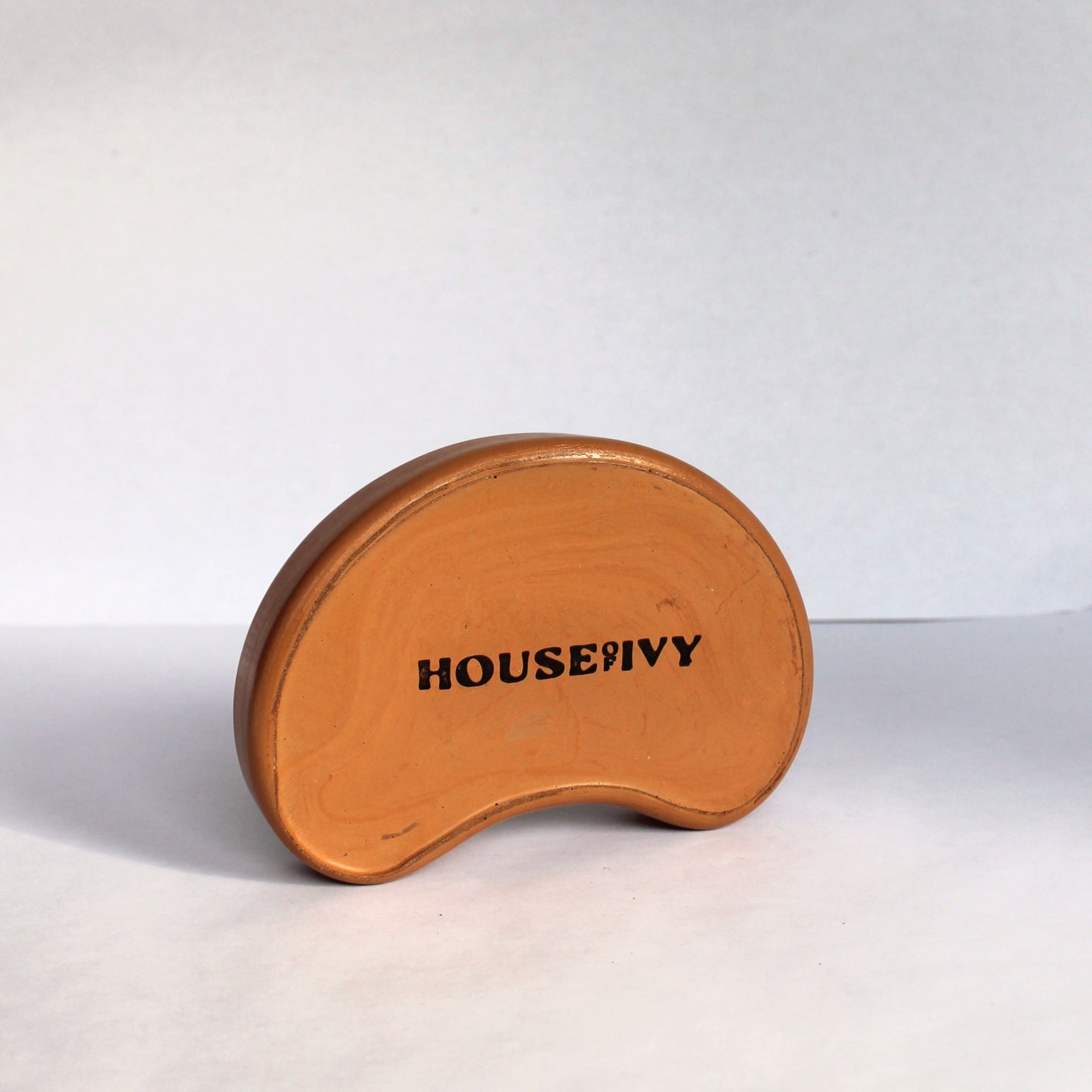 Back side of bean-shaped concrete tray with 'HOUSE OF IVY' branding on a white background