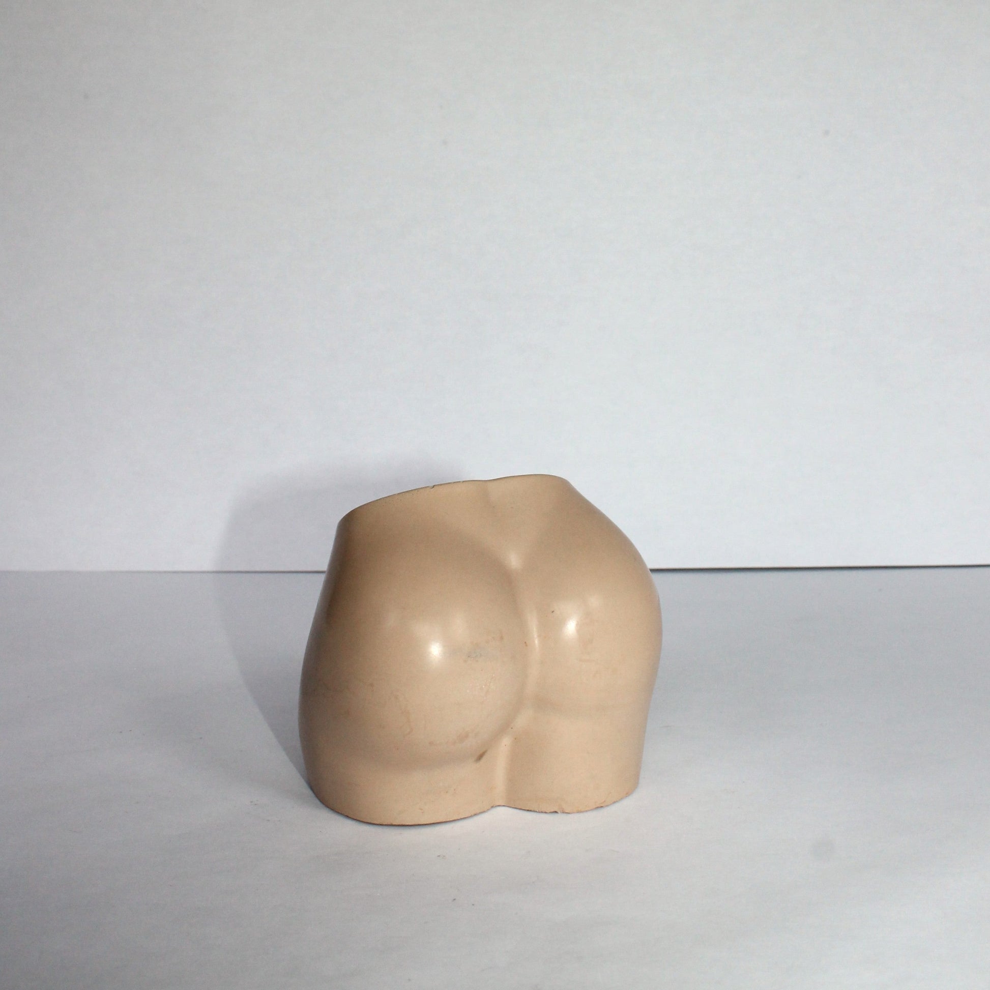 Beige concrete sculpture of body on a white background