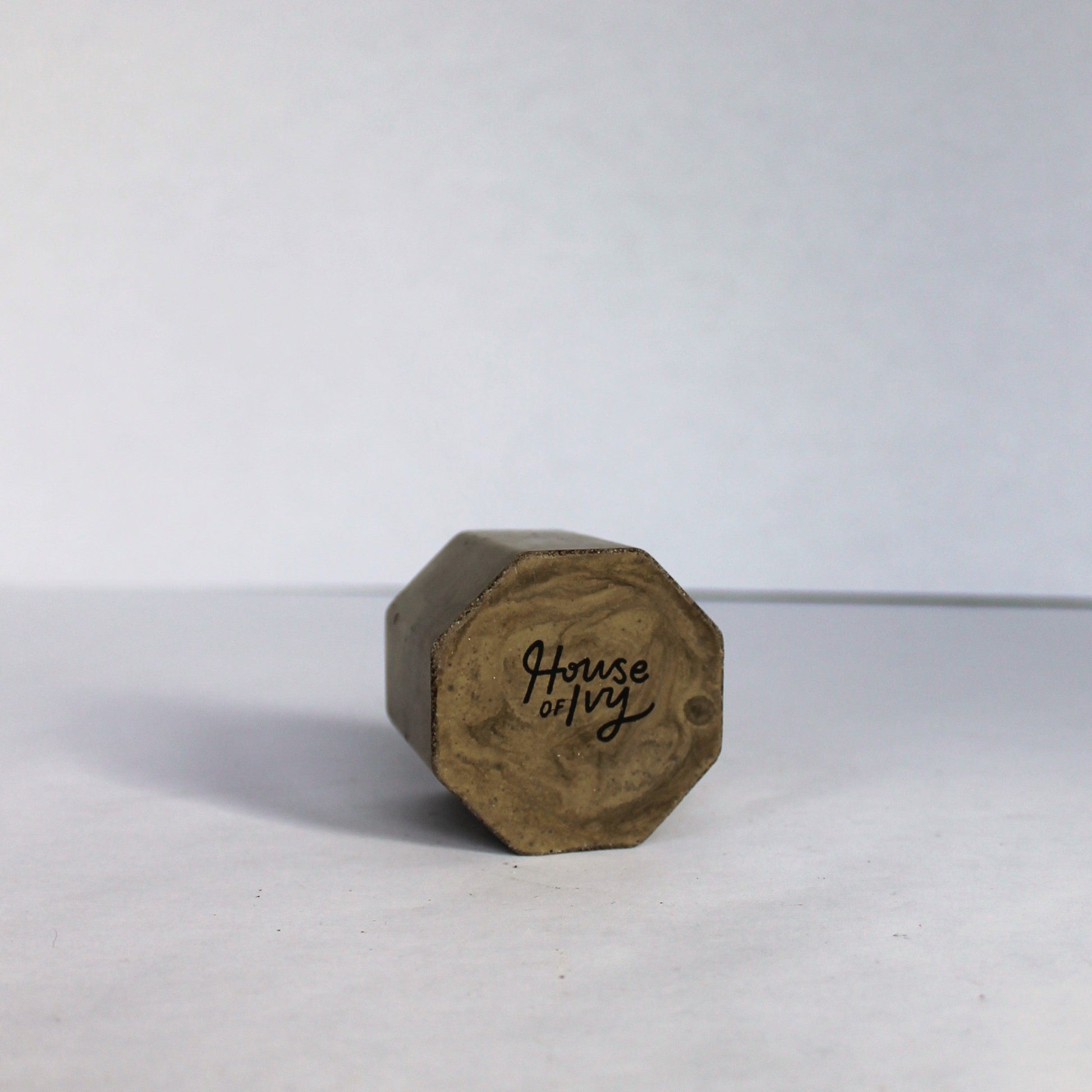 Bottom of a green hexagonal concrete vessel with 'House of Ivy' branding on a white background