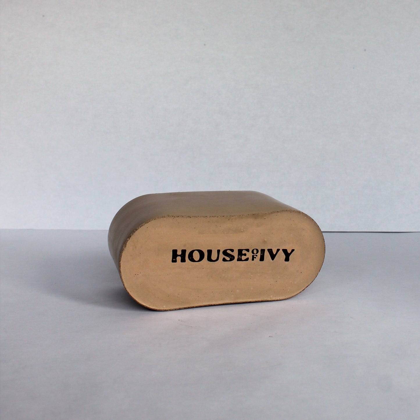 Bottom of concrete oval dish with 'HOUSE OF IVY' branding on a white background
