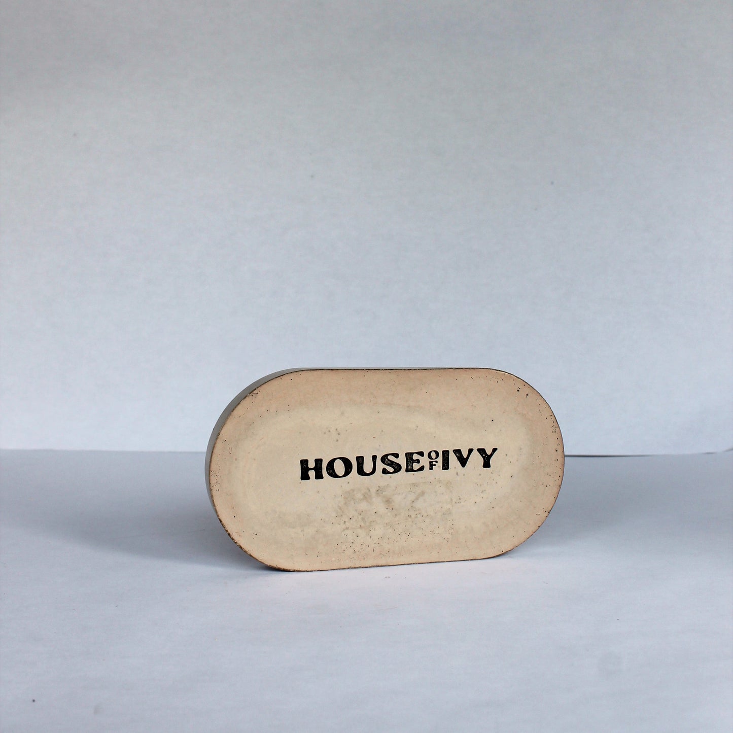 Bottom of concrete oval tray with 'House of Ivy' branding on a white background