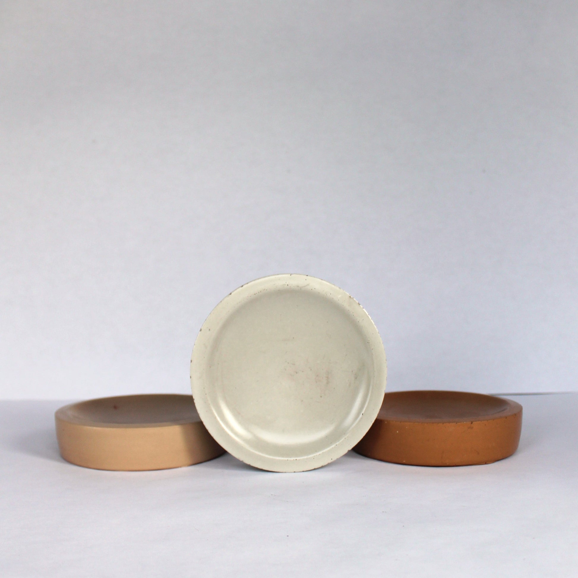 Three neutral concrete bowls on a white background
