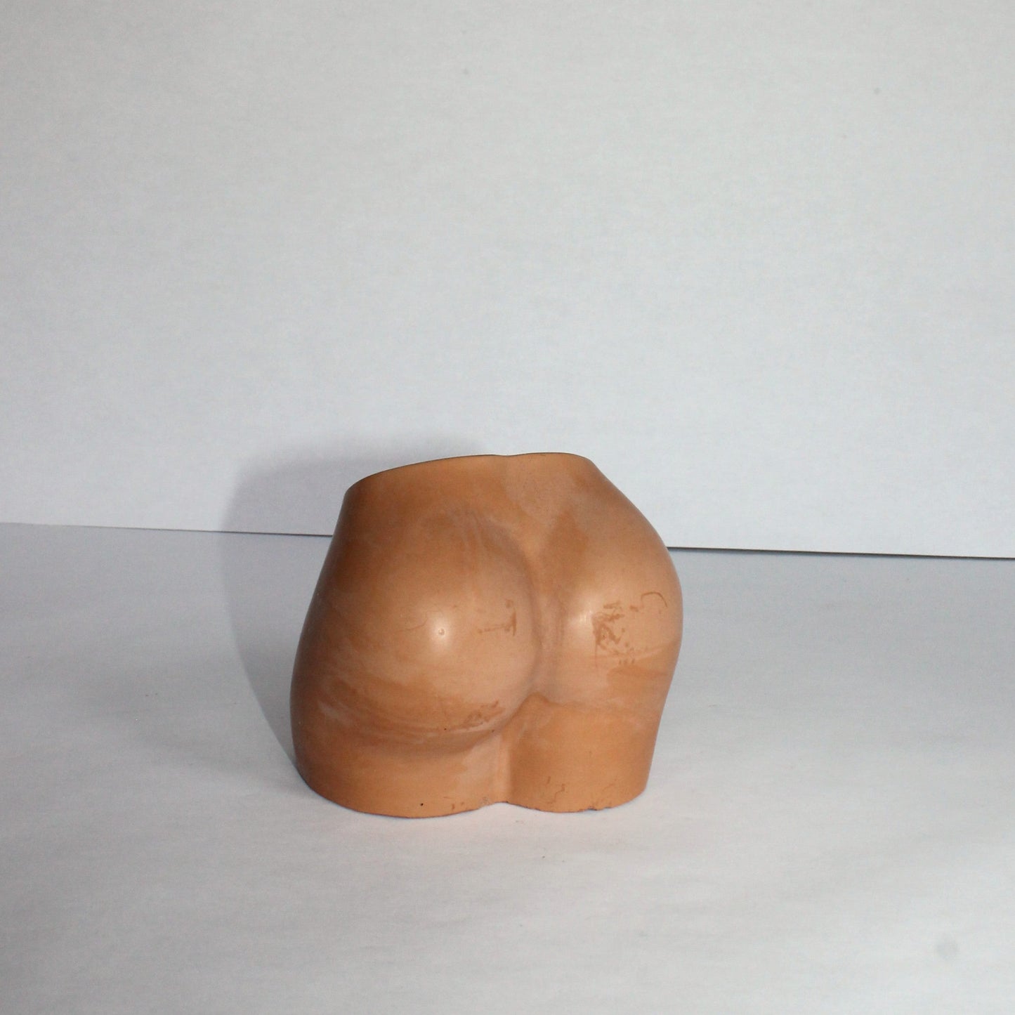 terracotta sculpture of a torso on a white background