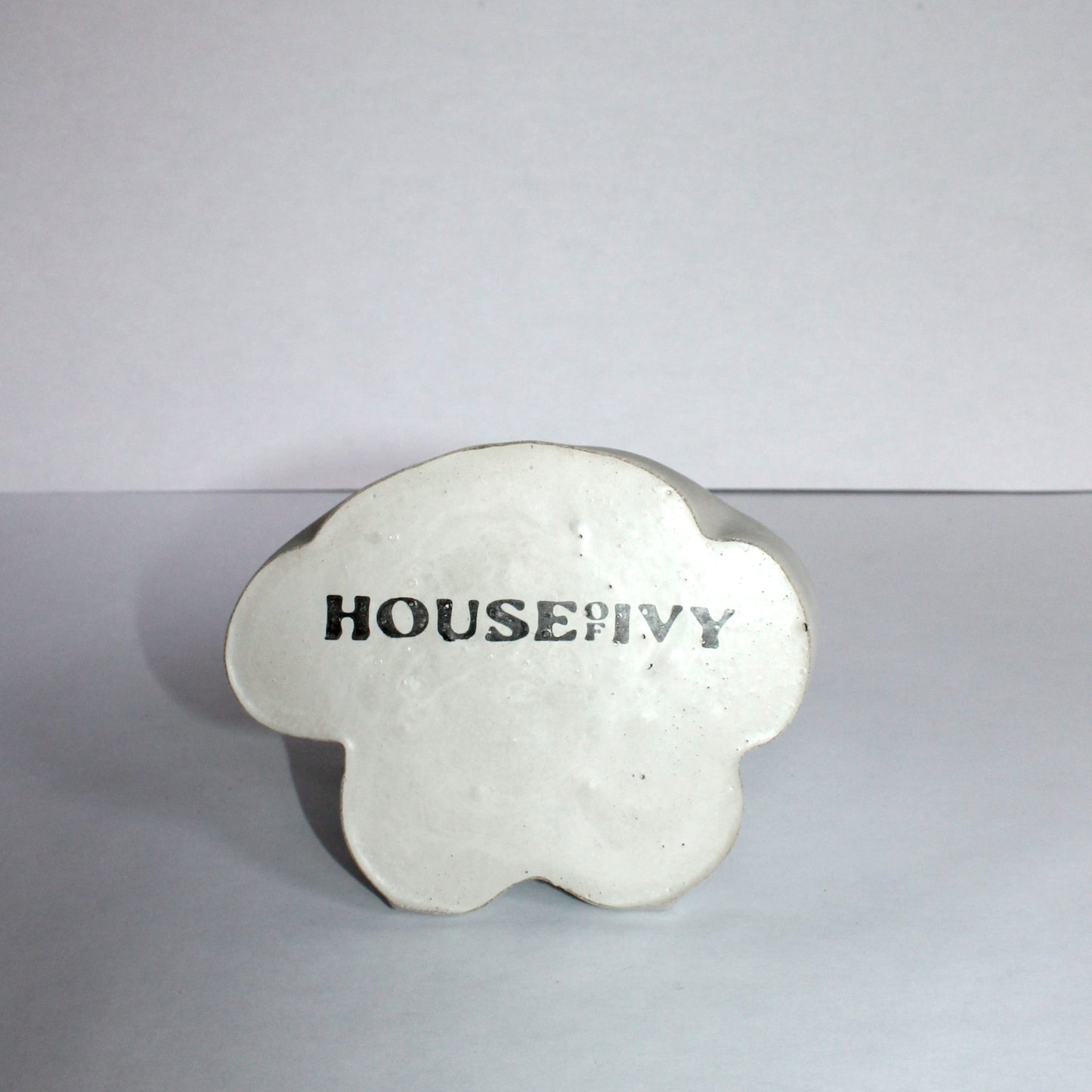Bottom of gray female bust shaped flower vase with 'House of Ivy' branding on a plain background