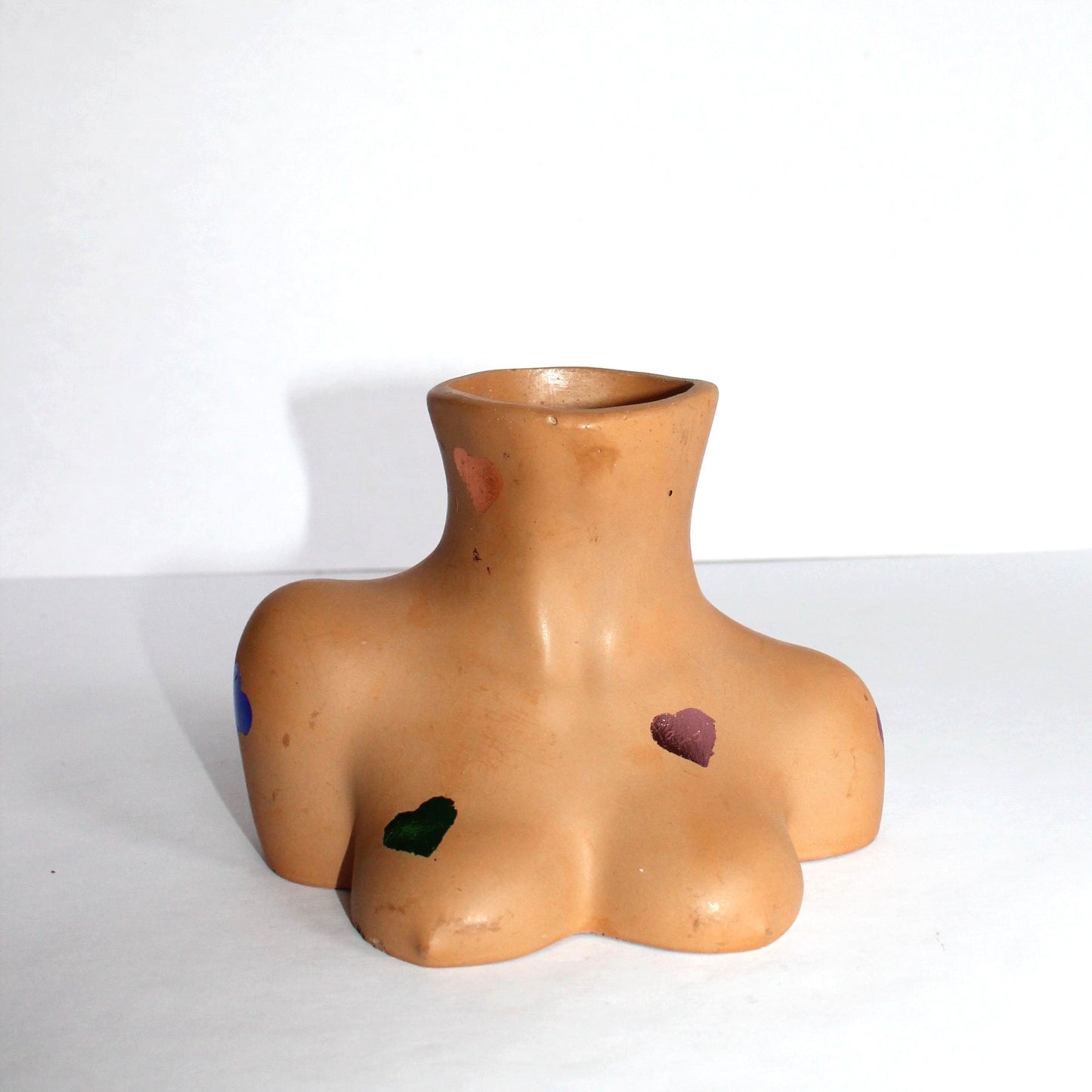 Vase shaped like a torso with decorative hearts on a white background