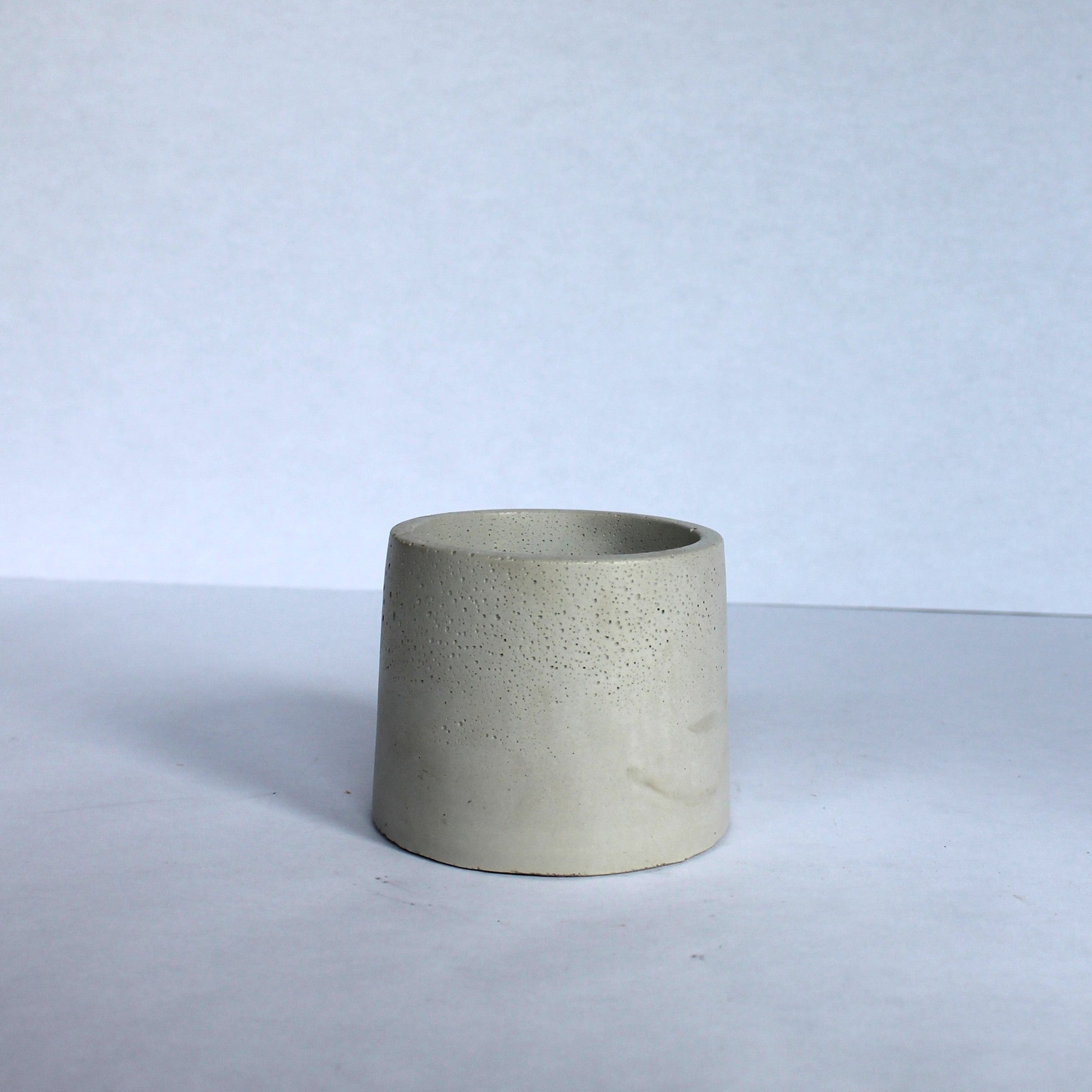 Cylindrical concrete planter on a light gray background