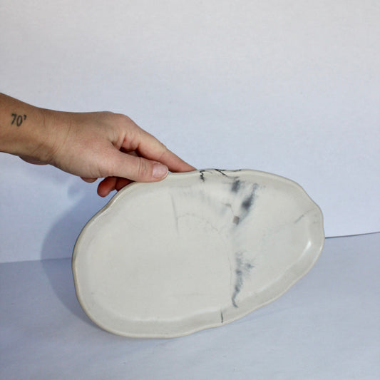 Hand holding a marble-patterned concrete tray against a white background