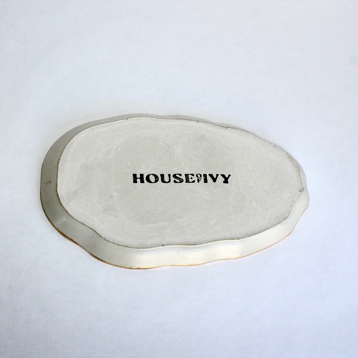 oval gray tray with metallic gold edge with 'HOUSE OF IVY' branding on a white background