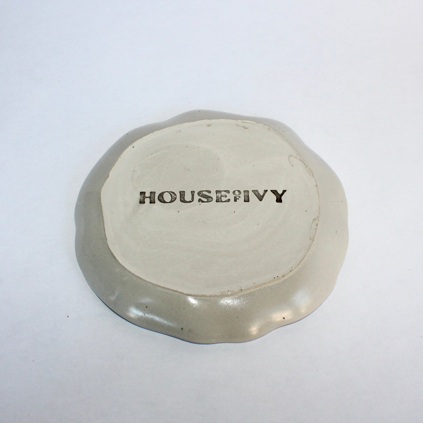 Round light gray decorative tray with 'House of Ivy' branding on a white background