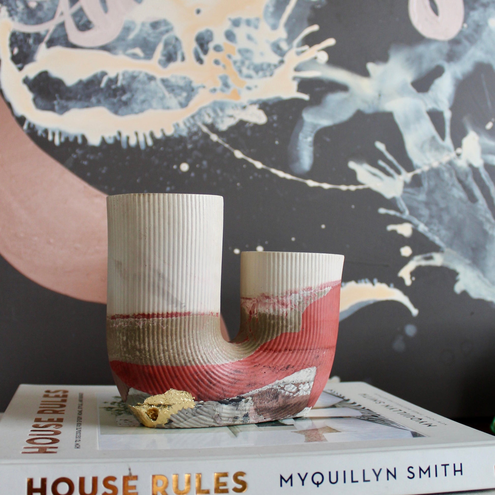 Decorative books with a concrete vase on top against a colorful abstract background