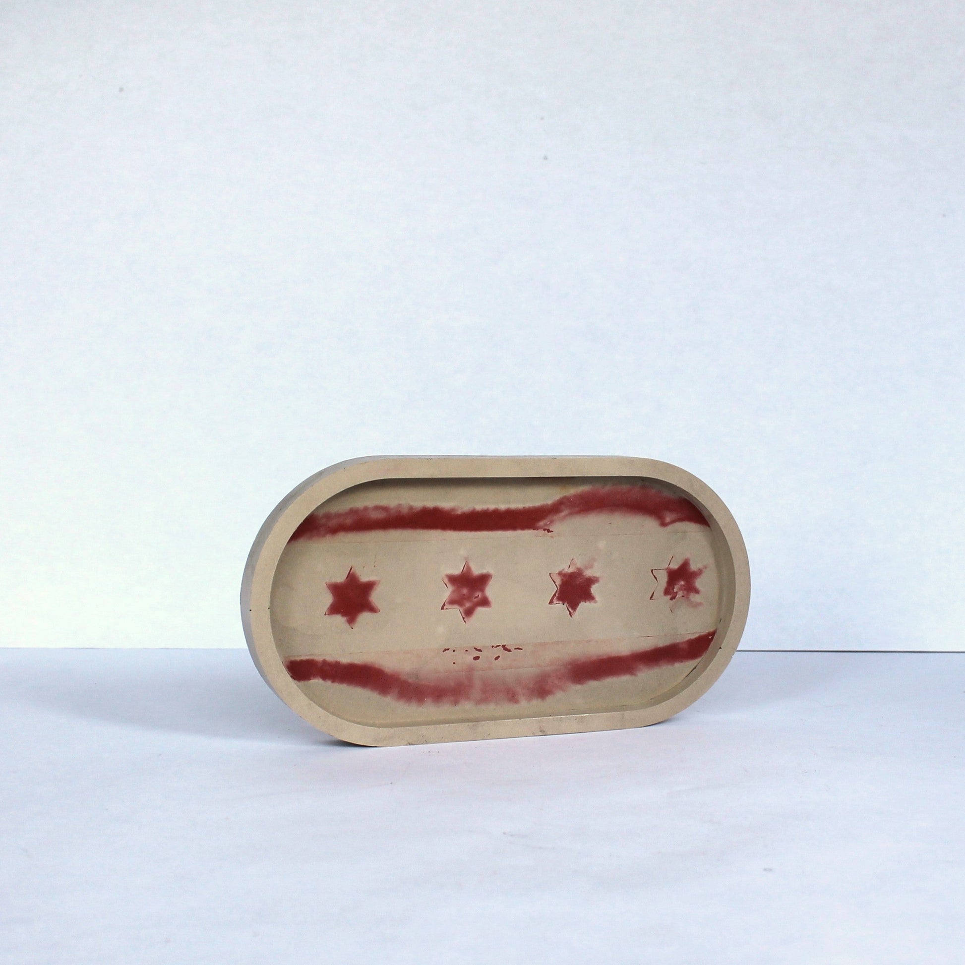 Small oval concrete dish with Chicago red star pattern on a white background