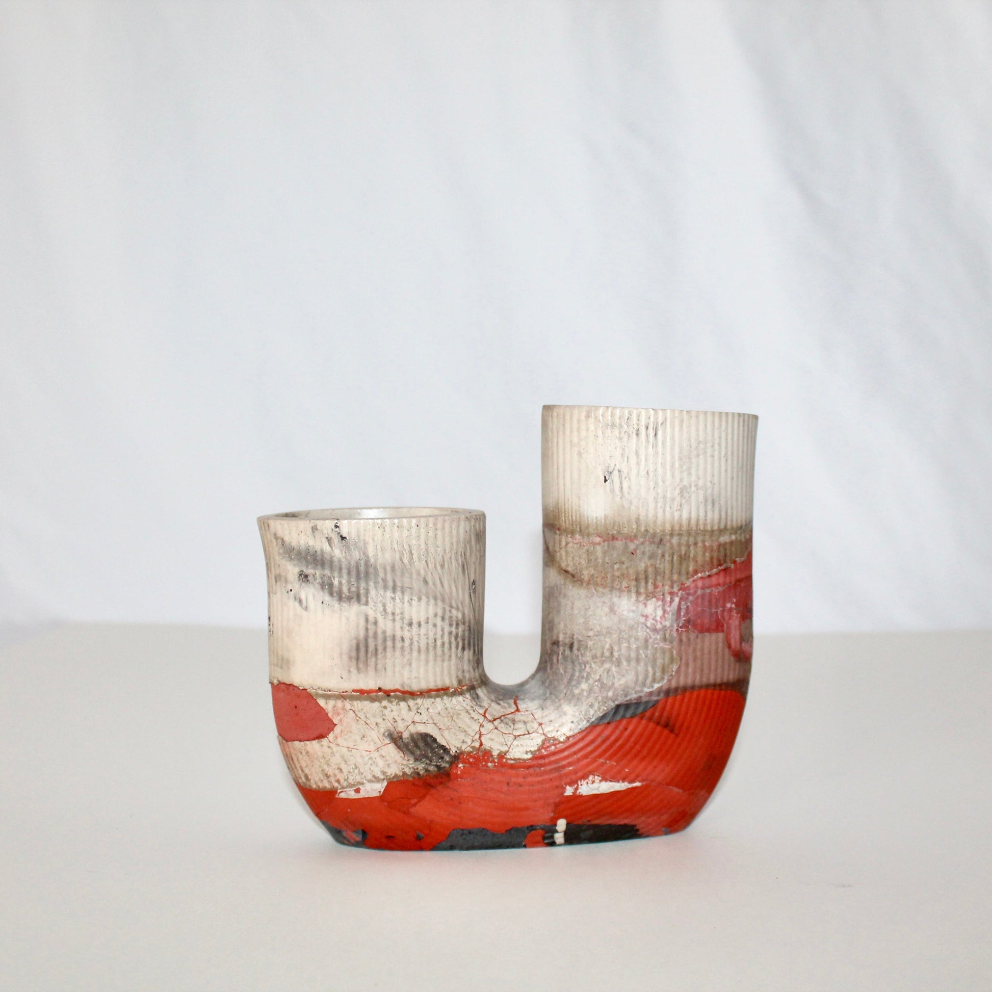beige and orange cement vase with abstract design on a white background