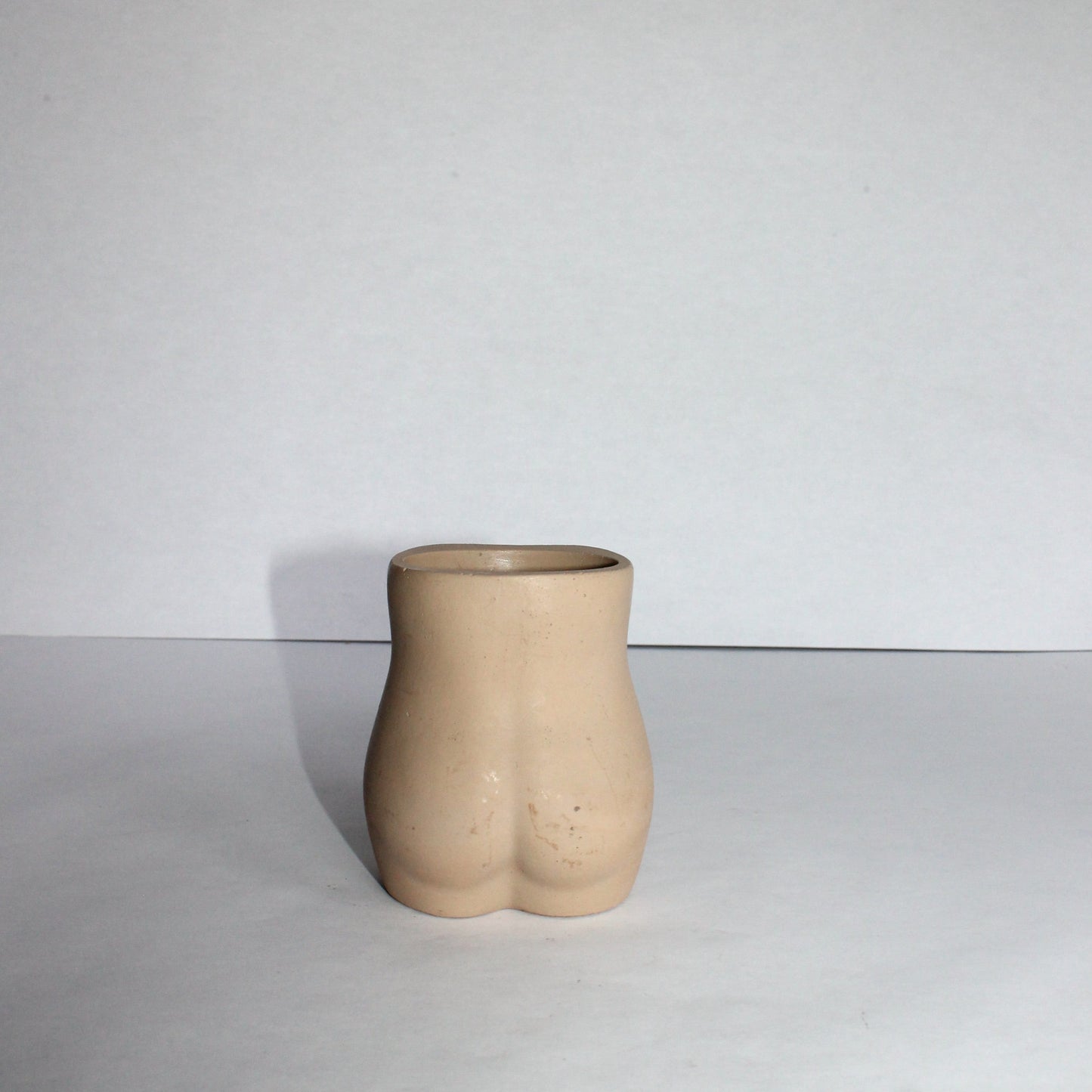 Concrete vase shaped like a female torso on a white background