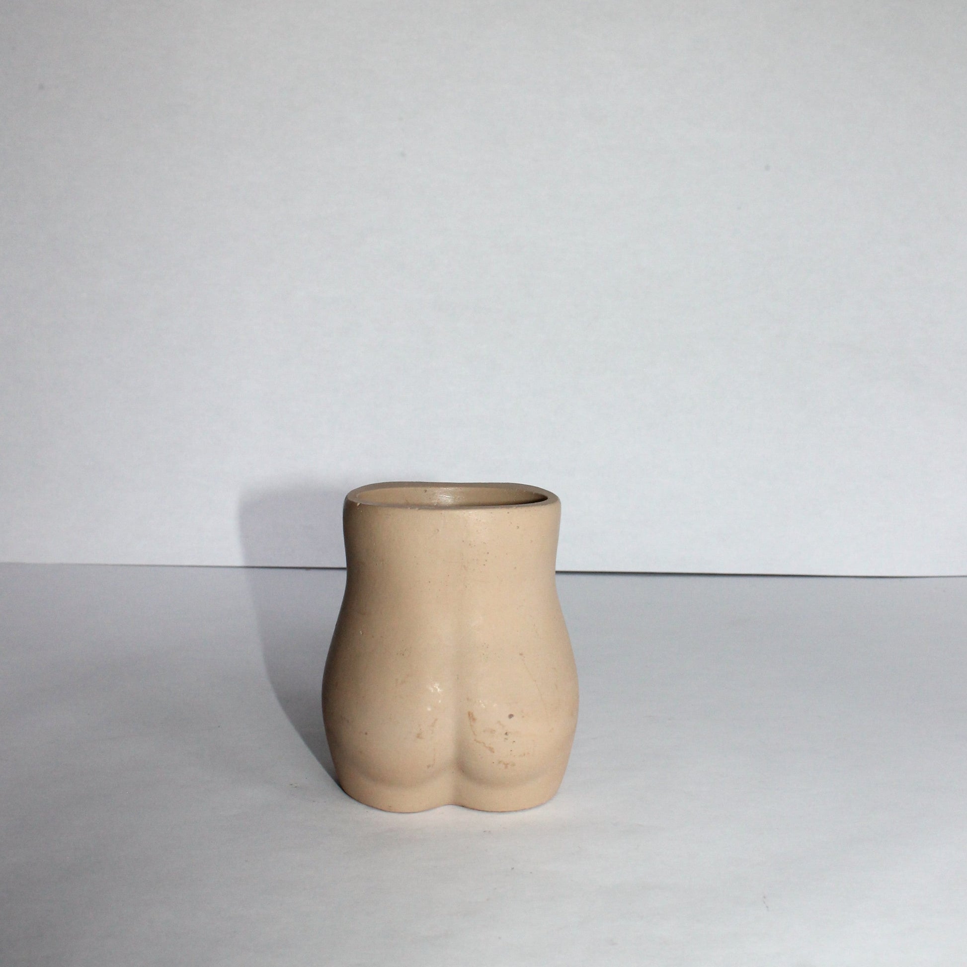 Concrete vase shaped like a female torso on a white background