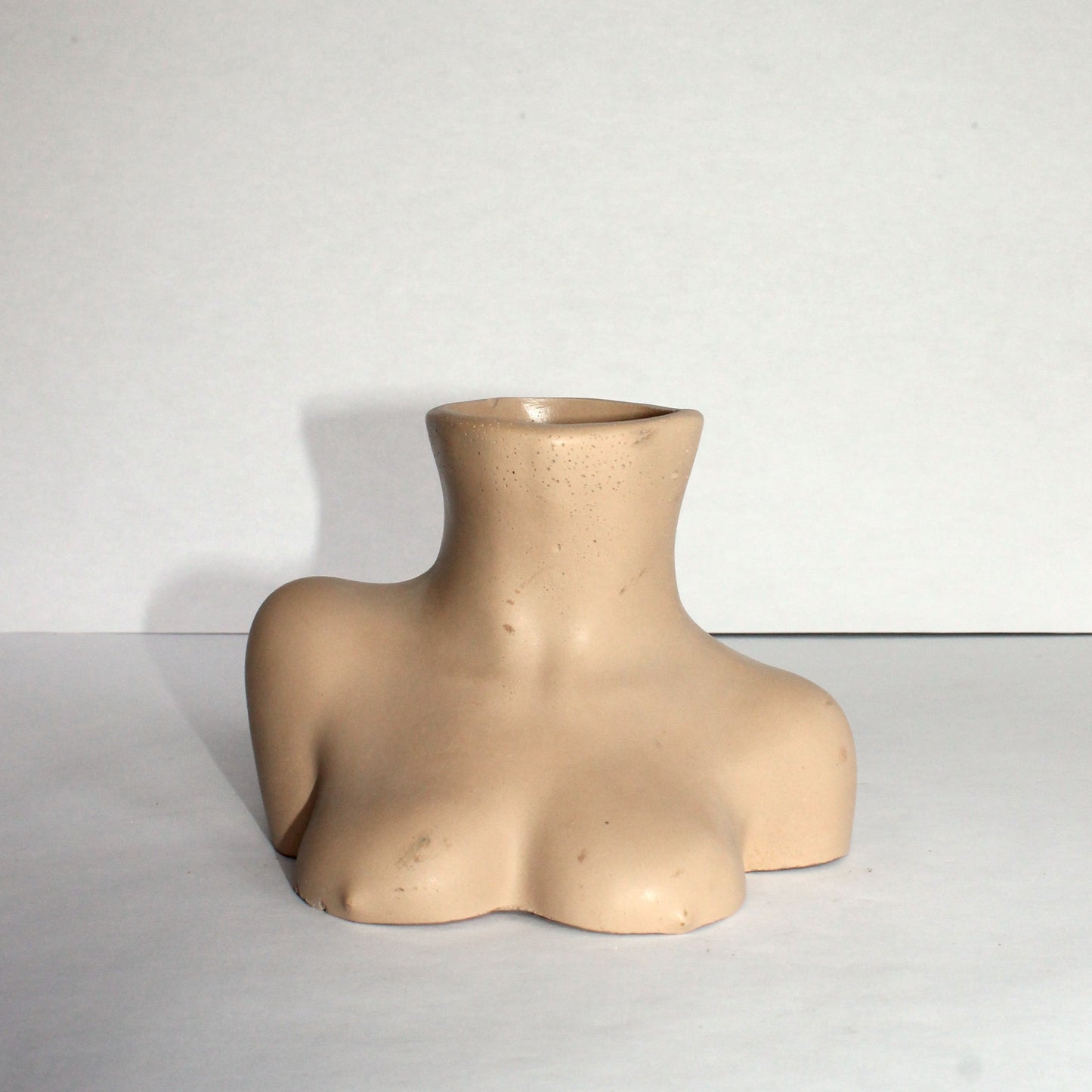 Beige female bust vase on a white surface with a white background