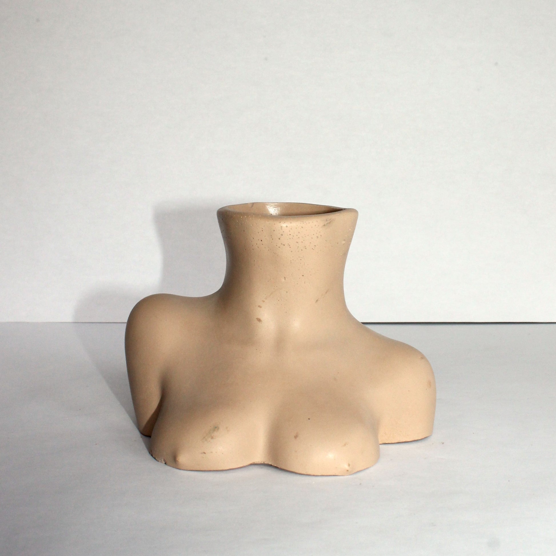 Beige female bust vase on a white surface with a white background