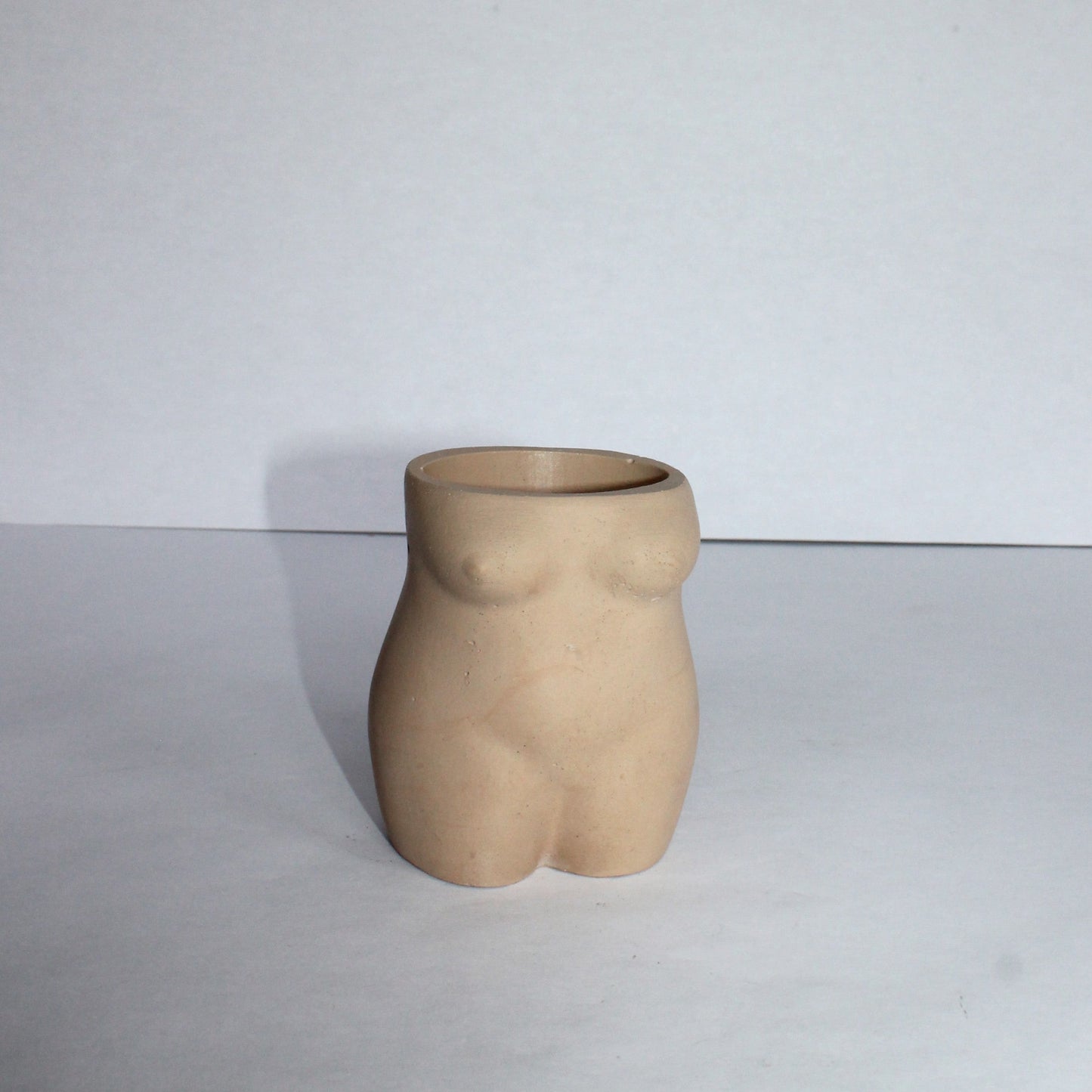 Concrete vase shaped like a female torso on a white background