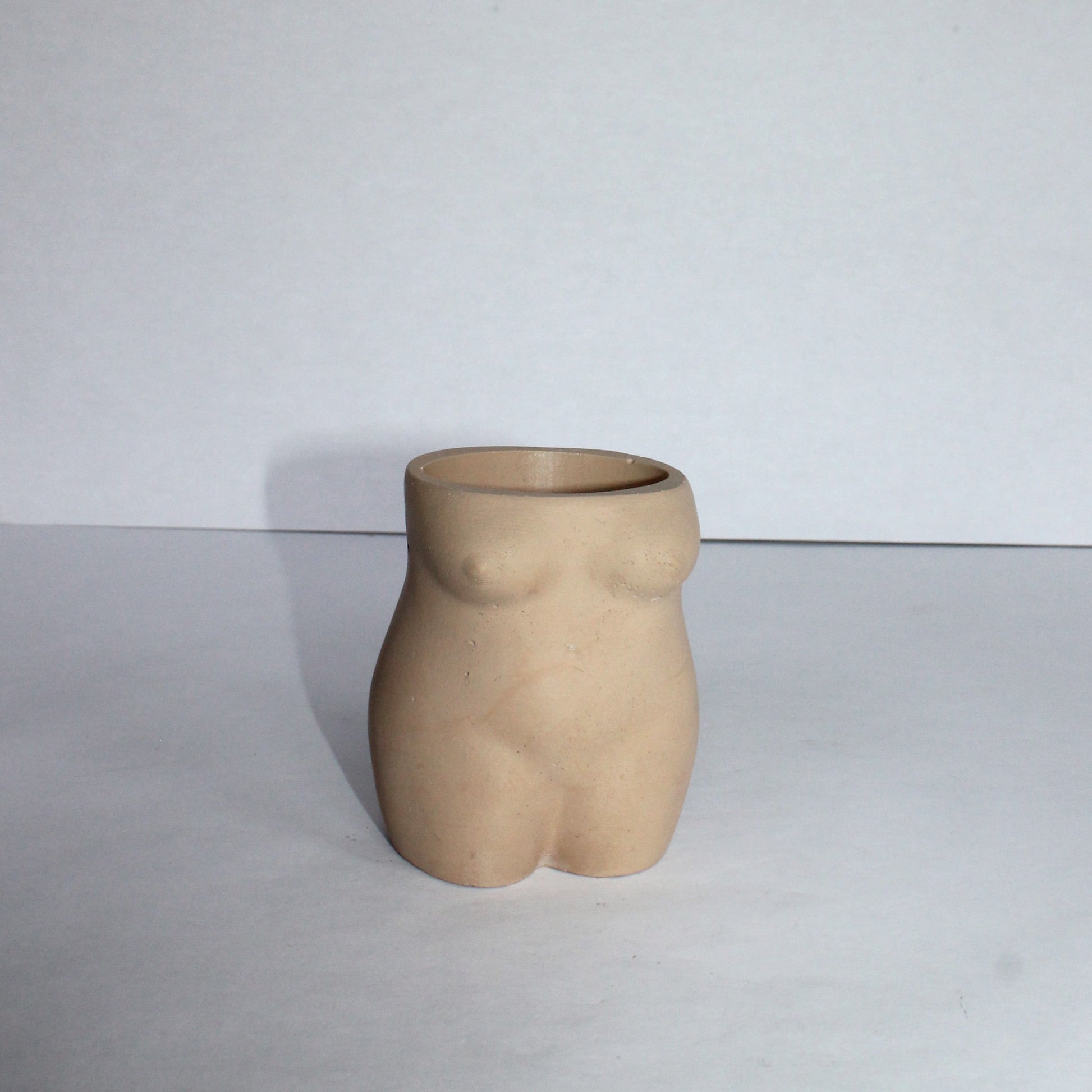 Concrete vase shaped like a female torso on a white background