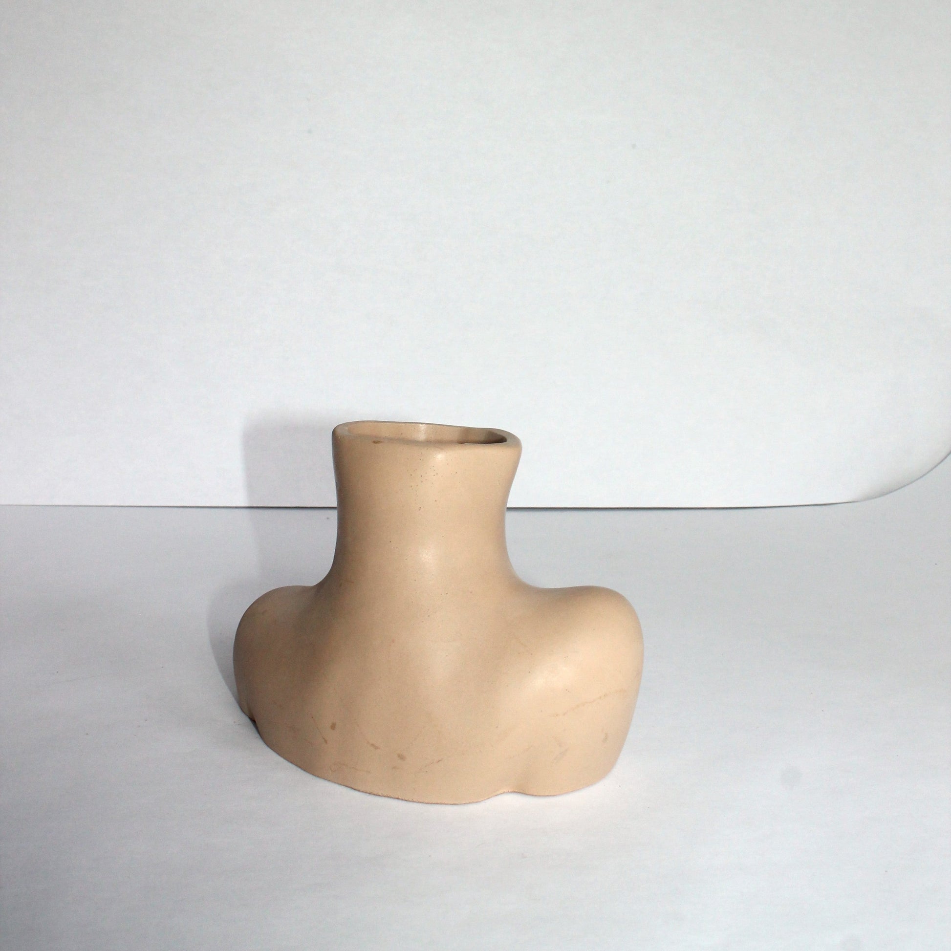 Back of beige female body concrete vase on a white background