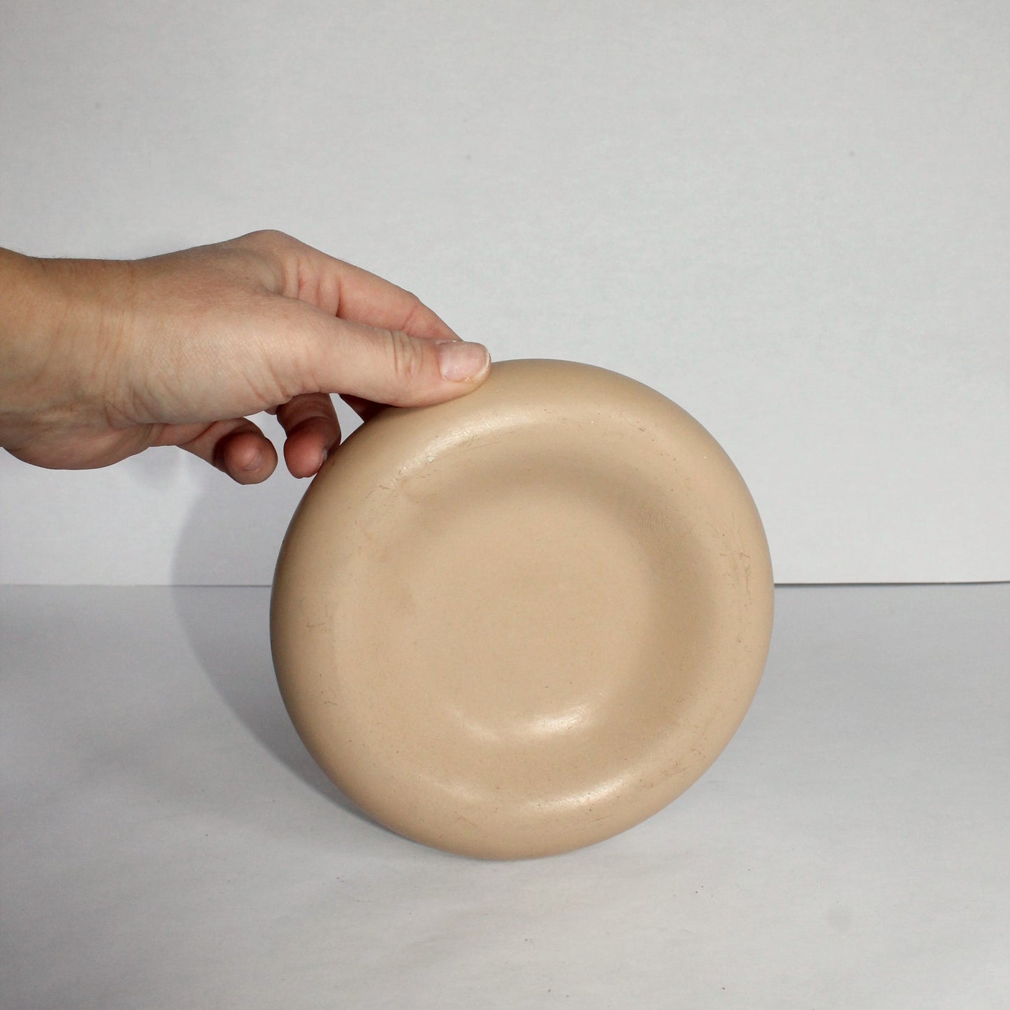 Beige concrete tray held by a hand against a plain background