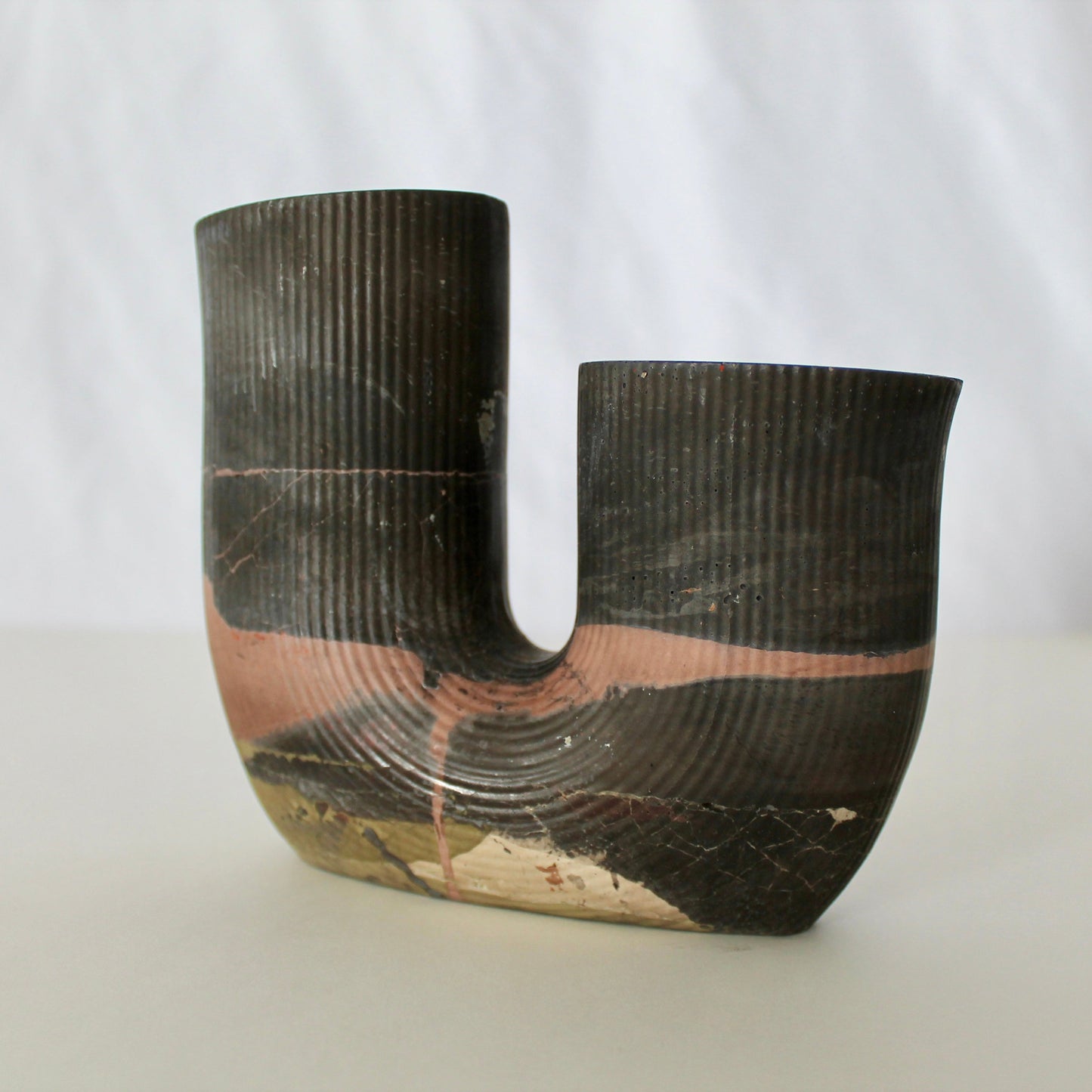 Black cement vase with textured surface on a white background