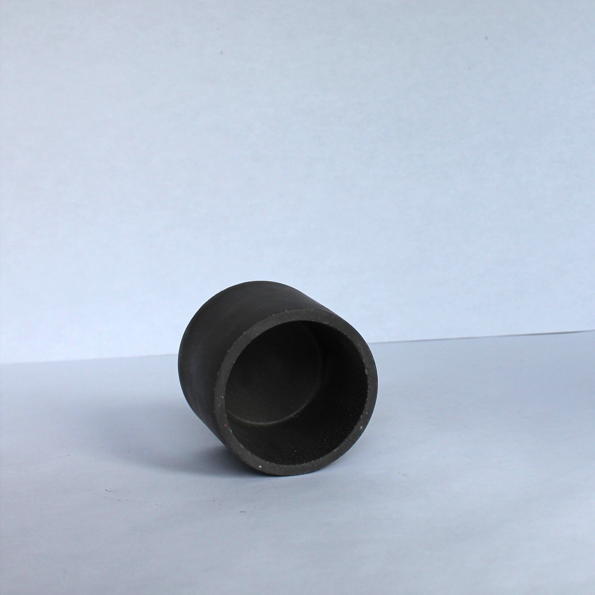 Black concrete cylindrical dish on a white background