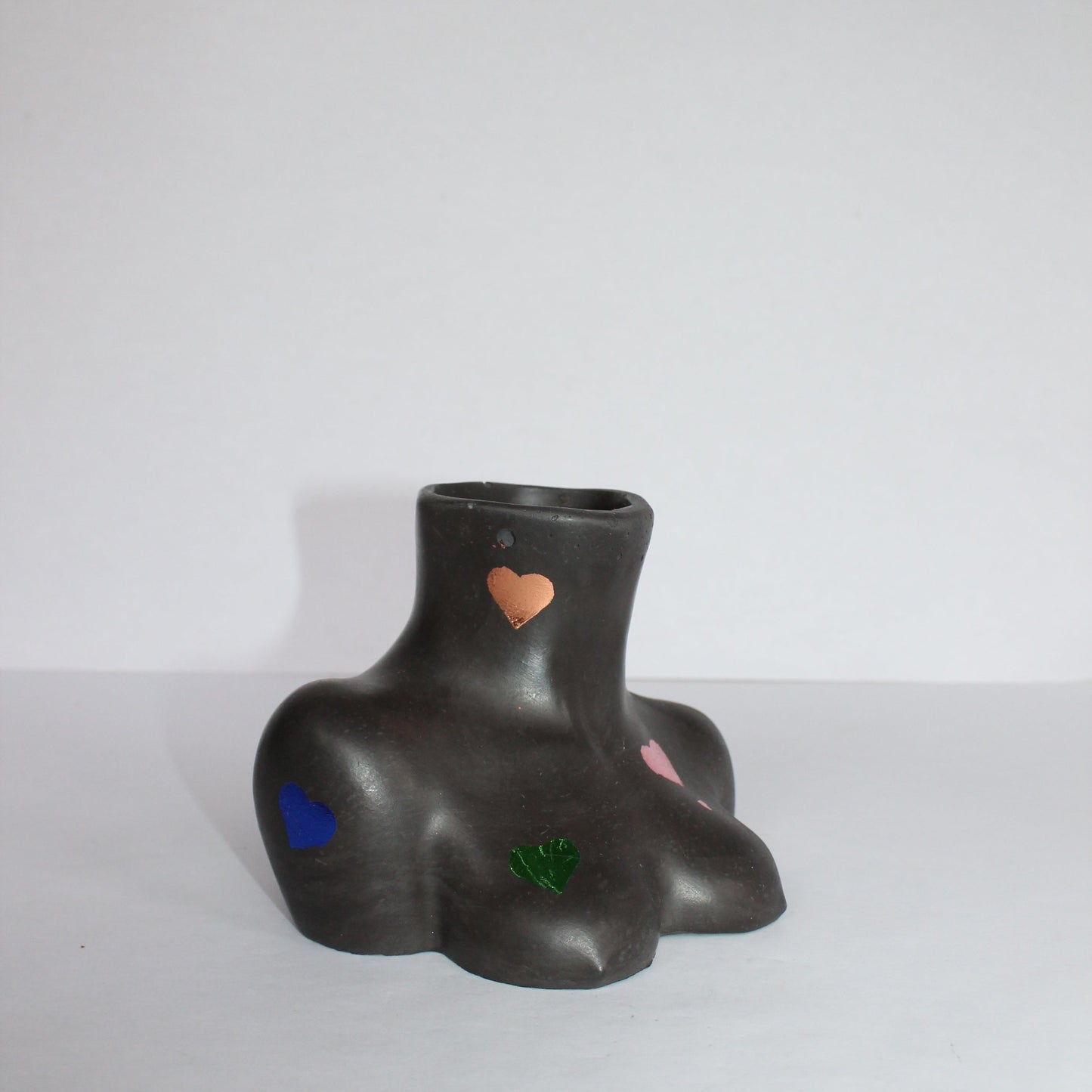 Black female body vase with colorful heart designs on a white background