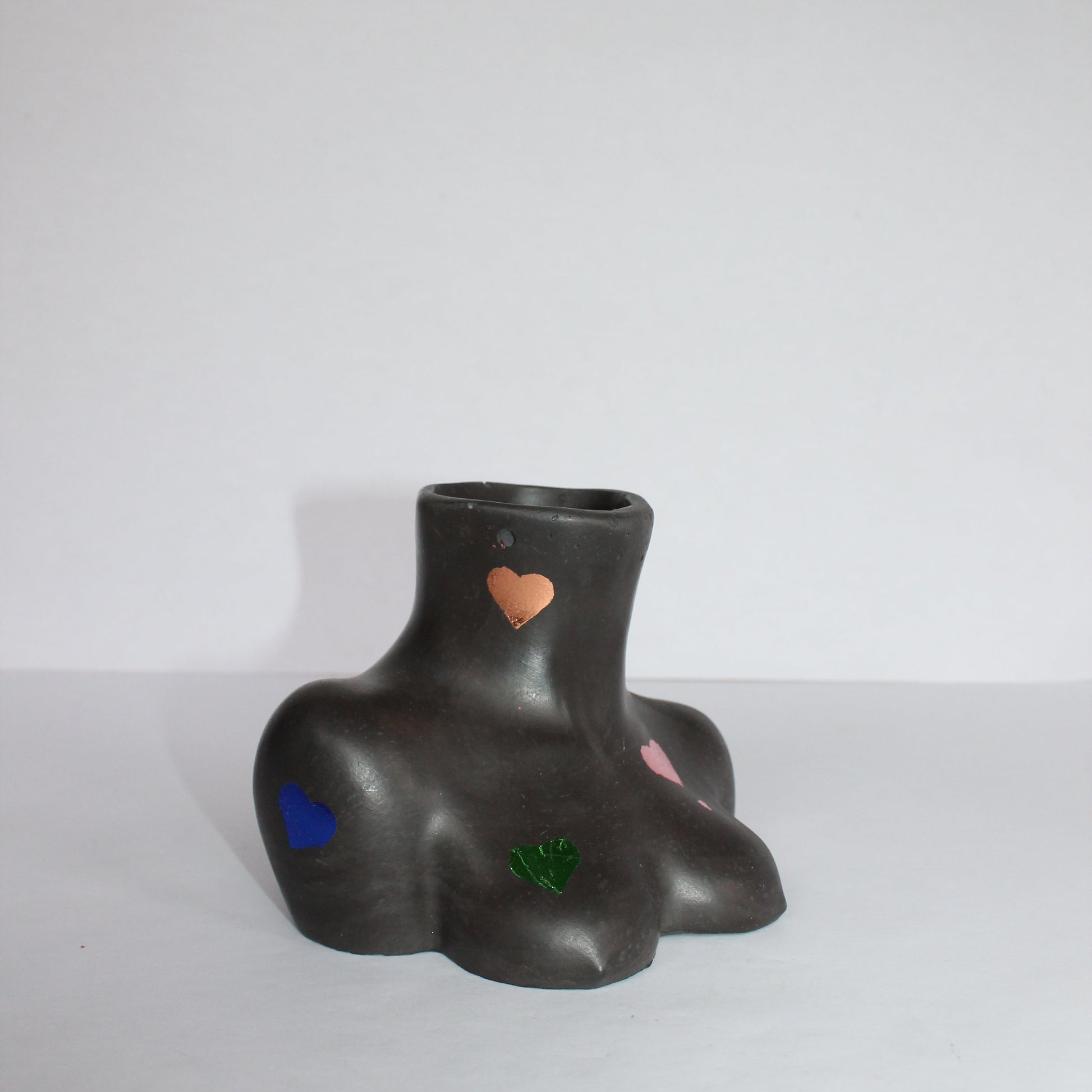 Black female body vase with colorful heart designs on a white background