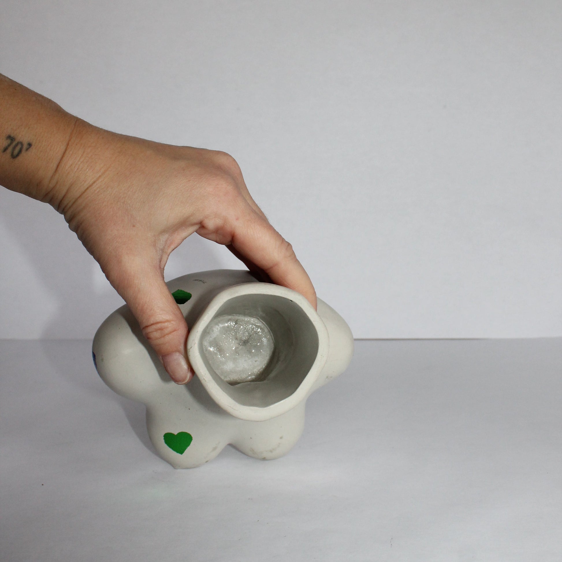 Hand holding a small light gray concrete pot against a plain background