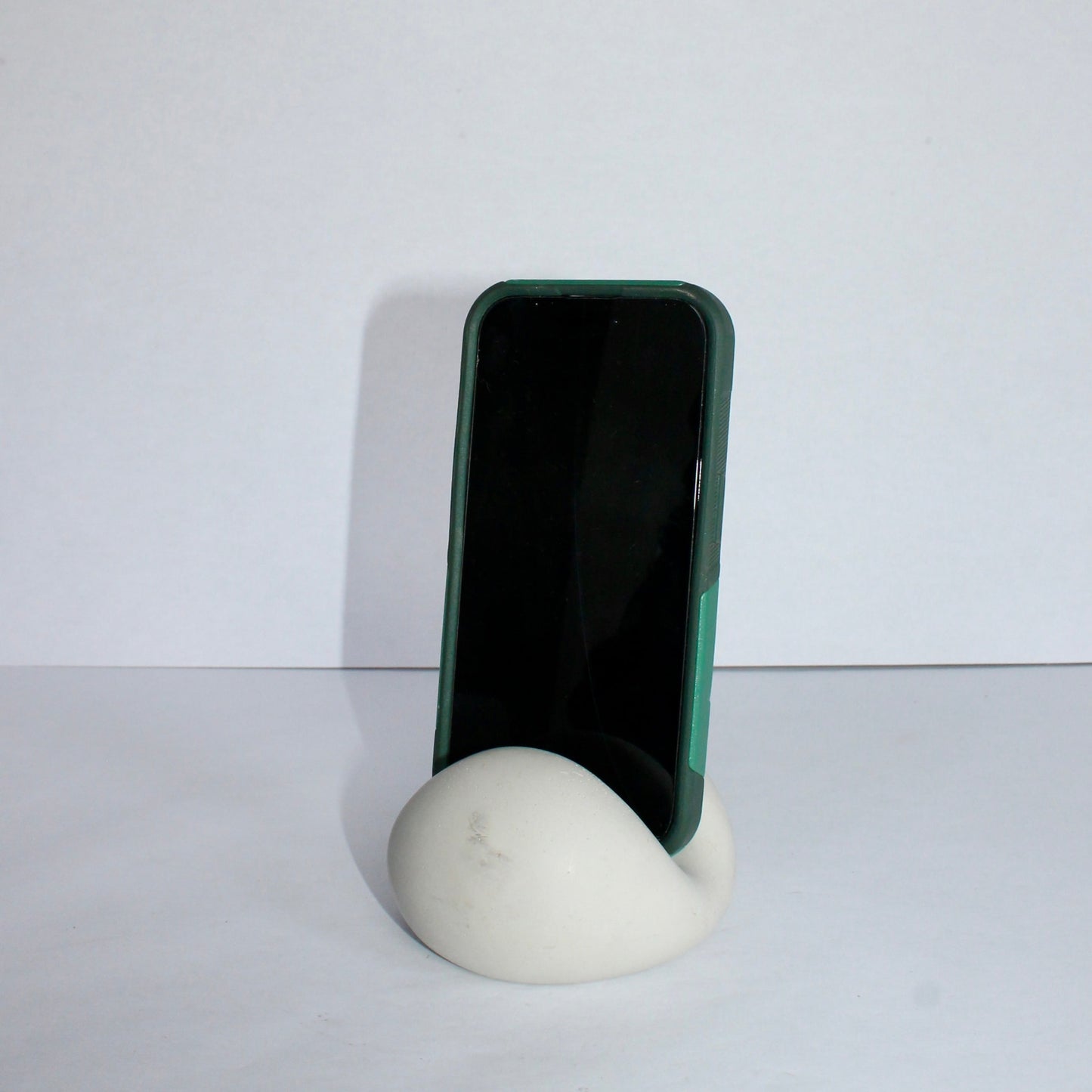 Light gray chic phone stand with phone on a plain background