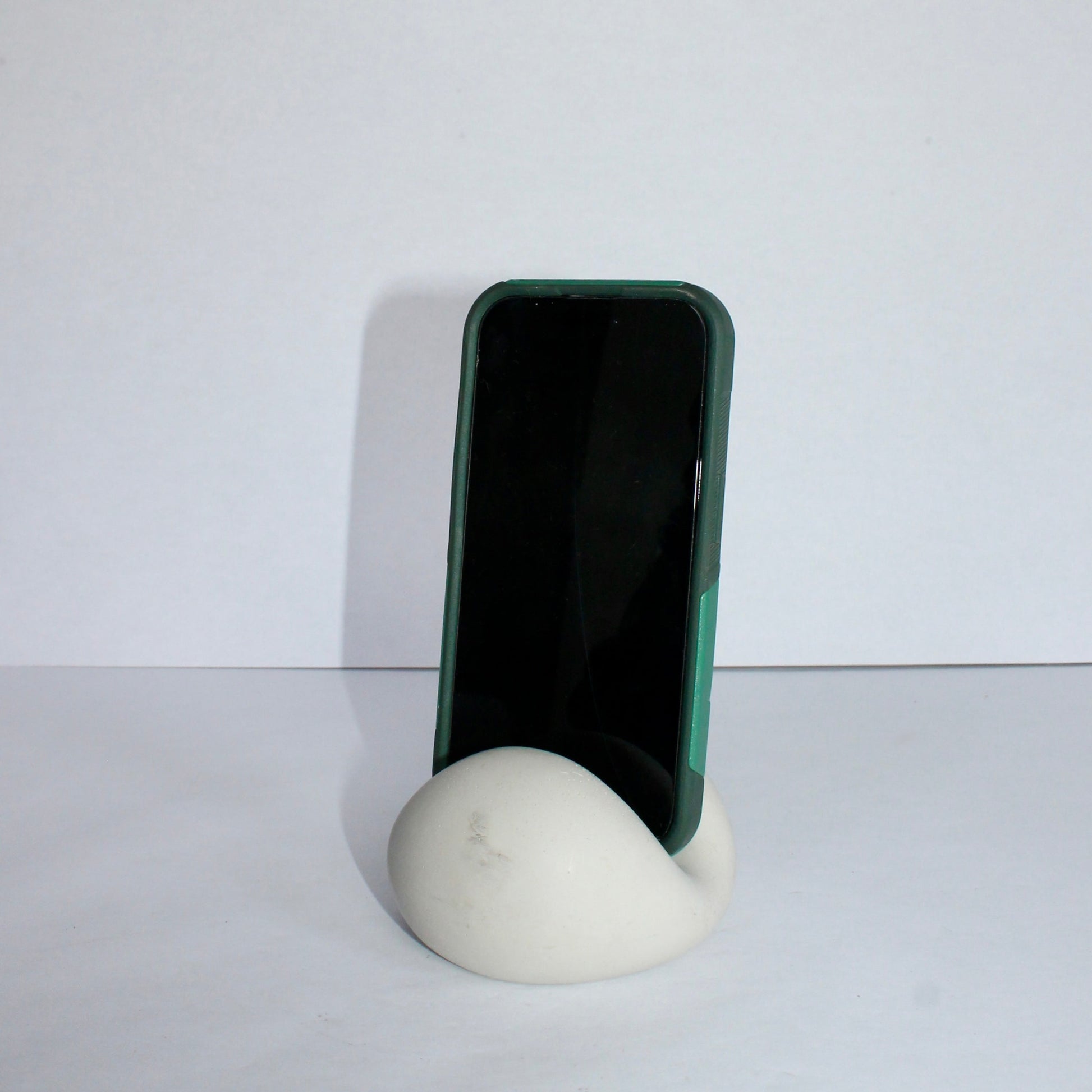 Light gray chic phone stand with phone on a plain background