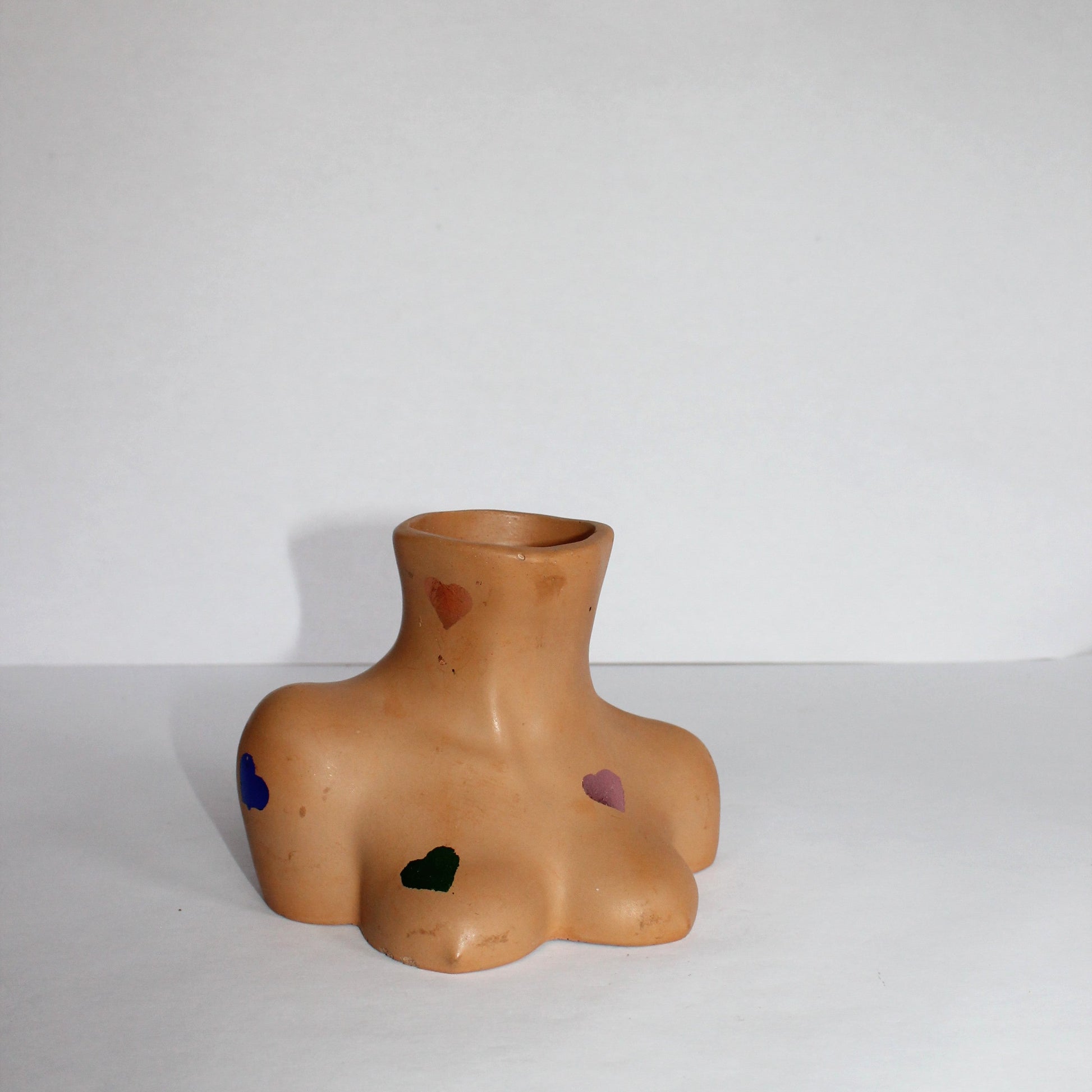Vase shaped like a female torso with multi-colored rainbow hearts on a white background
