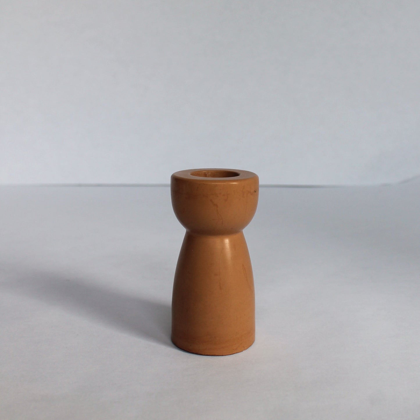 Clay colored concrete candle holder on a white background