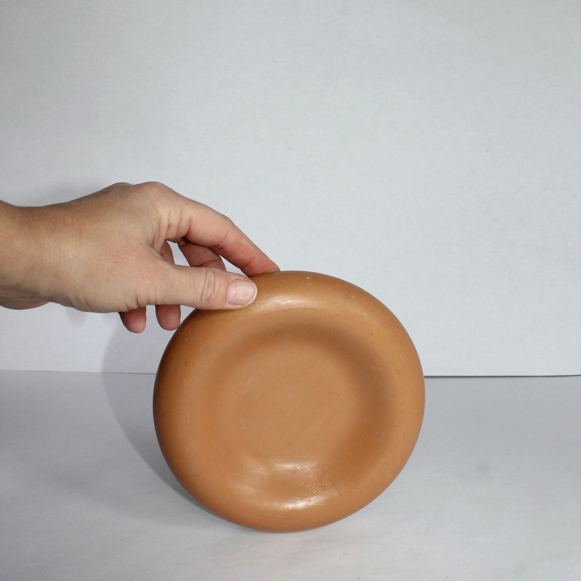 Hand holding a terracotta concrete tray against a white background