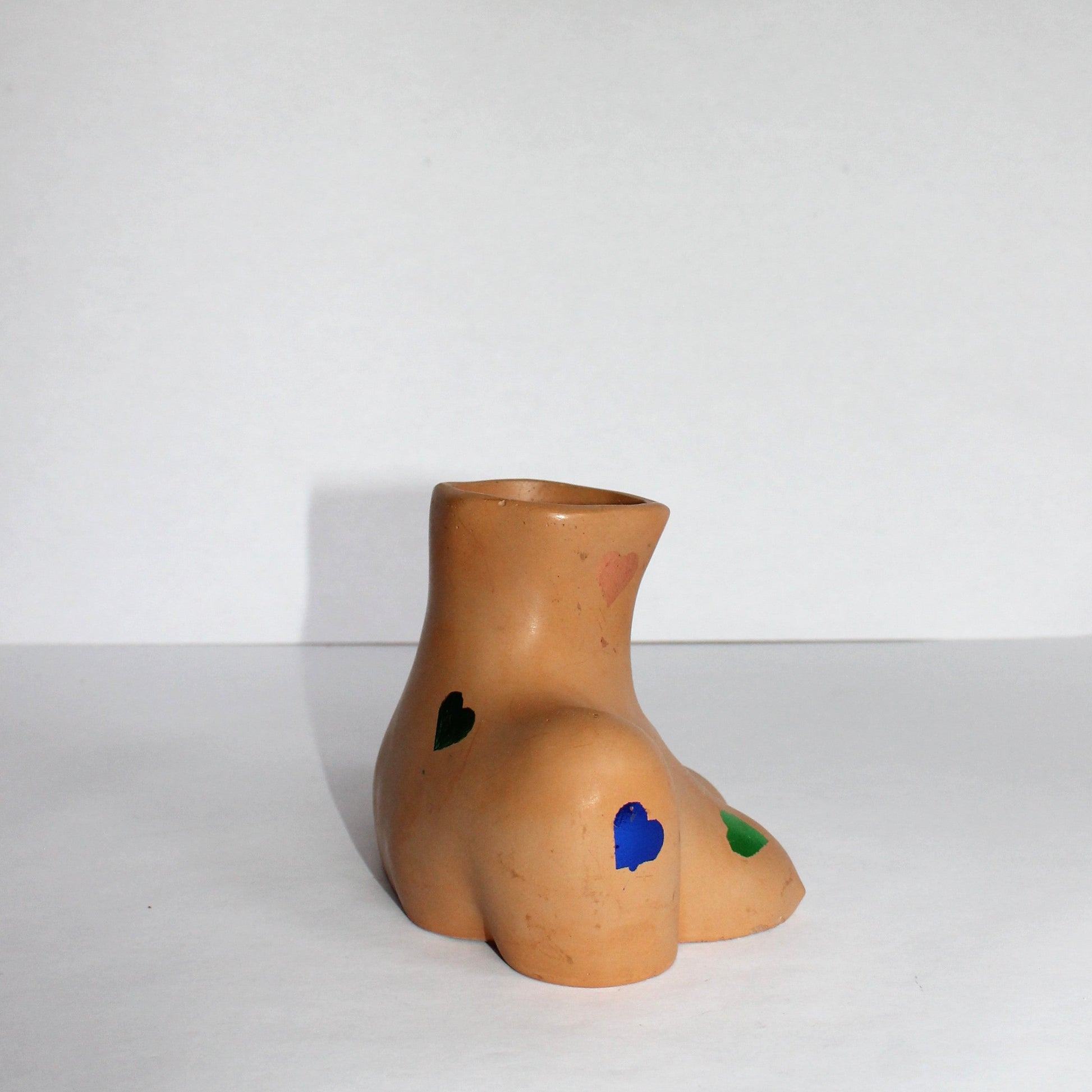concrete vase, side profile of a female silhouette, with multi-colored gold foiled hearts on a white background
